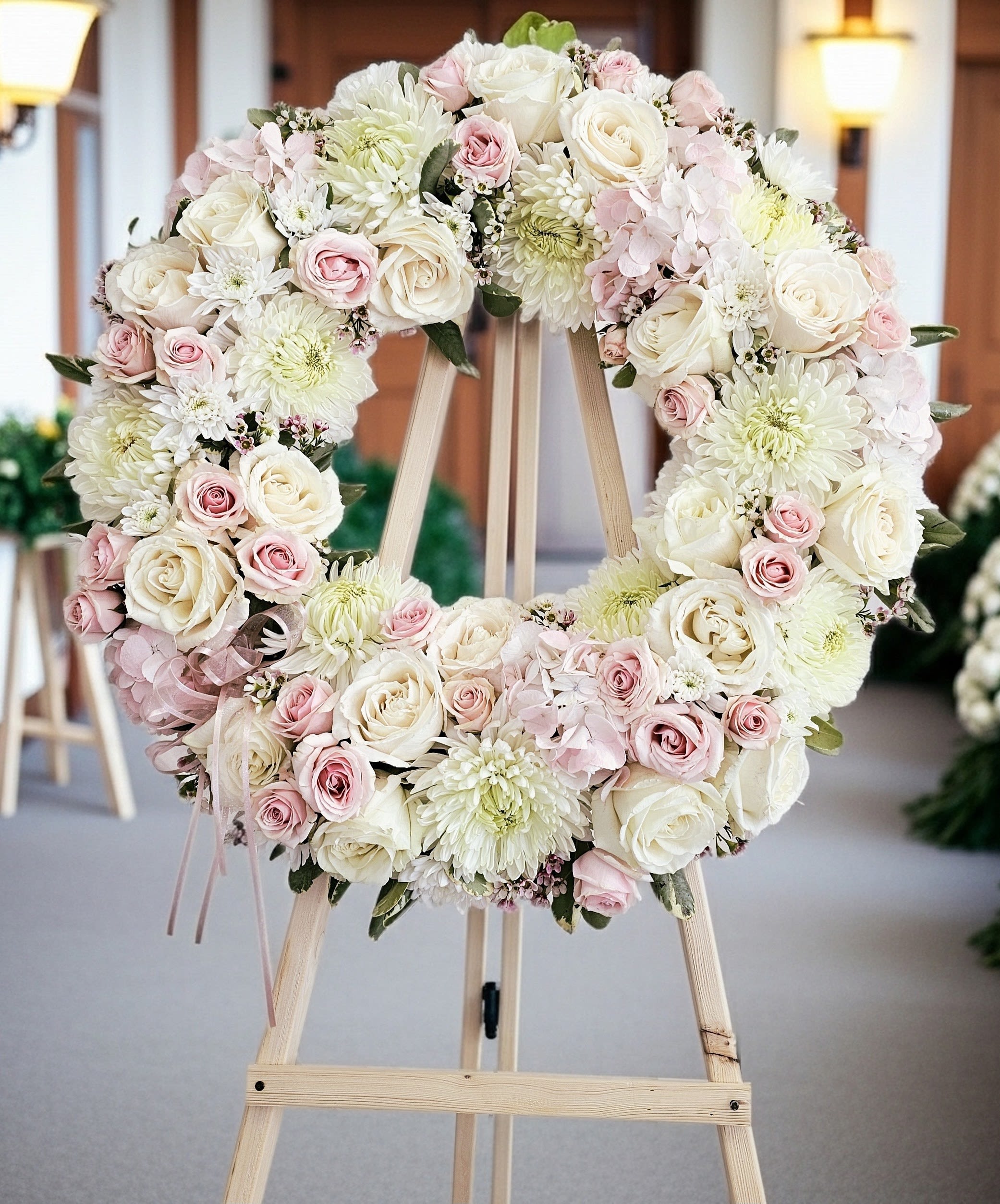 Heart-shaped floral wreath of white and pink roses on a wooden easel