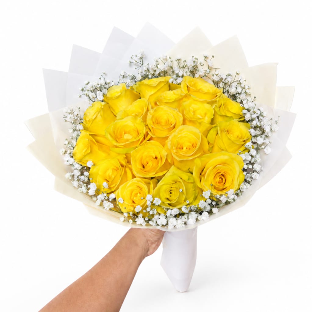 Bouquet of yellow roses with small white filler flowers wrapped in white paper