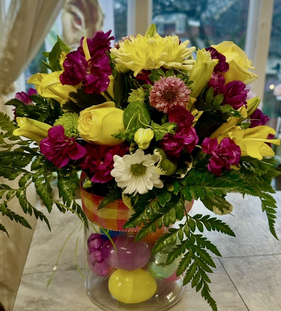 EASTER SURPRISES CANISTER ARRANGEMENT - BEATIFUL DOUBLE DECKER CANNISTER ARRANGEMENT THAT SHOWCASES PLASTIC EGGS ON THE BOTTOM AND A DESIGNER DISH ON TOP FILLED WITH GREENS, LILLIES, ROSES, CARNATIONS, MUMS AND DAISEYS. SURE TO BRING A WOW TO THIS EASTER