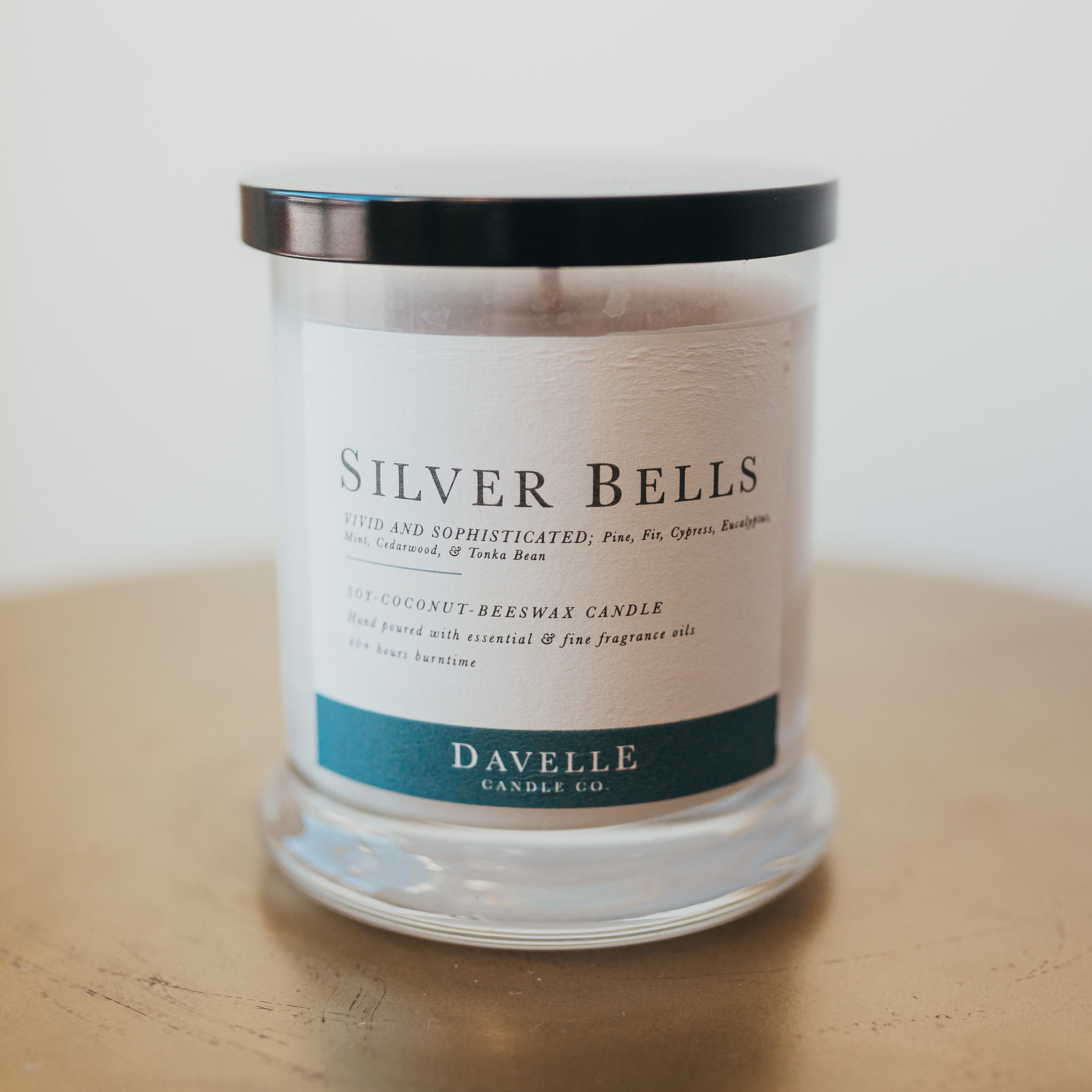 A scented candle in a clear glass jar with a black lid