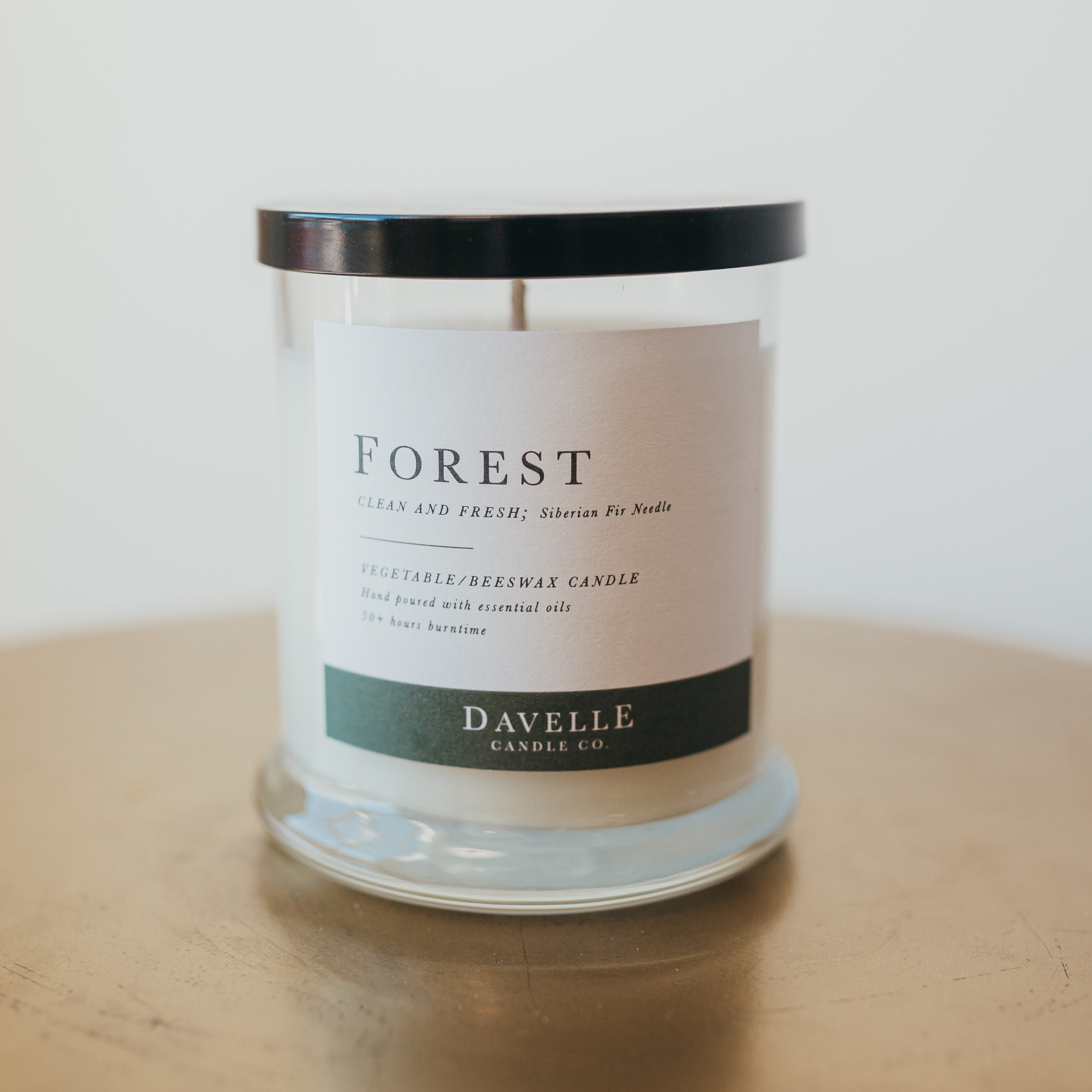 Glass jar candle with a black lid and forest label
