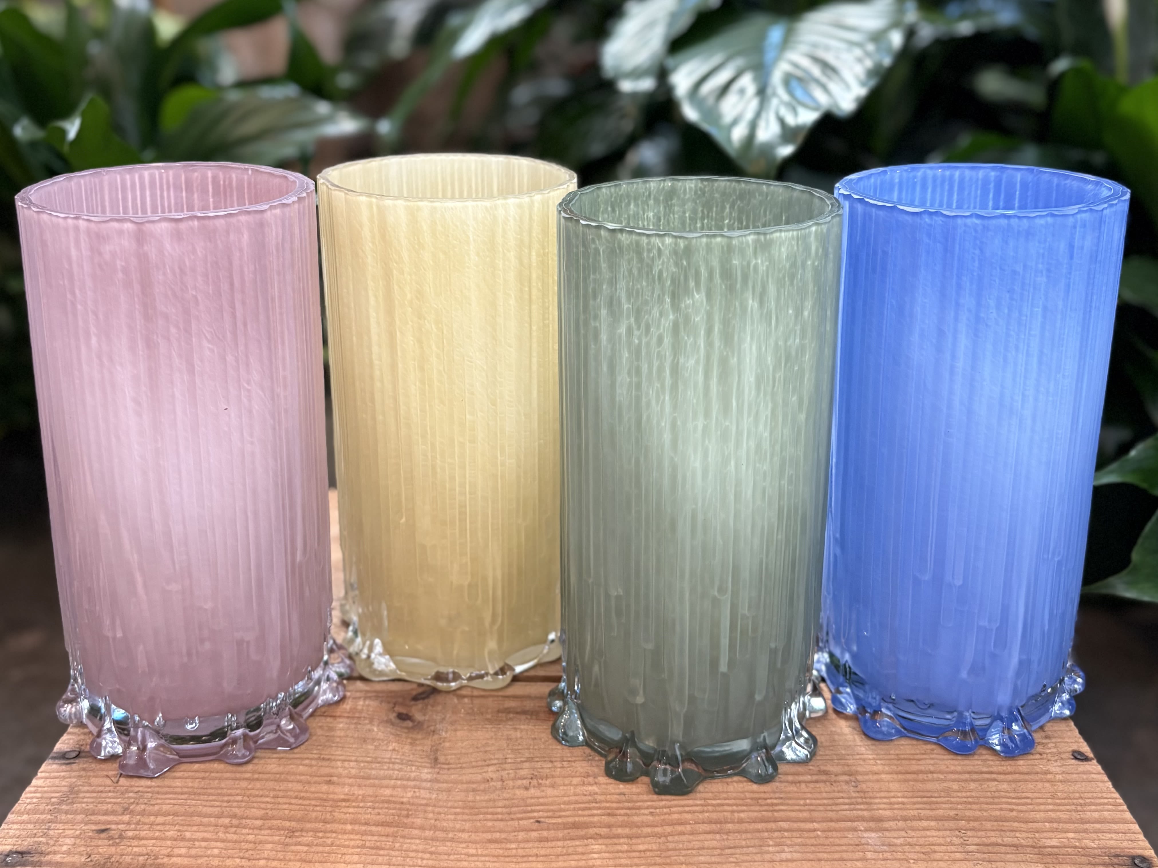 Four colored glass candle holders on a wooden surface
