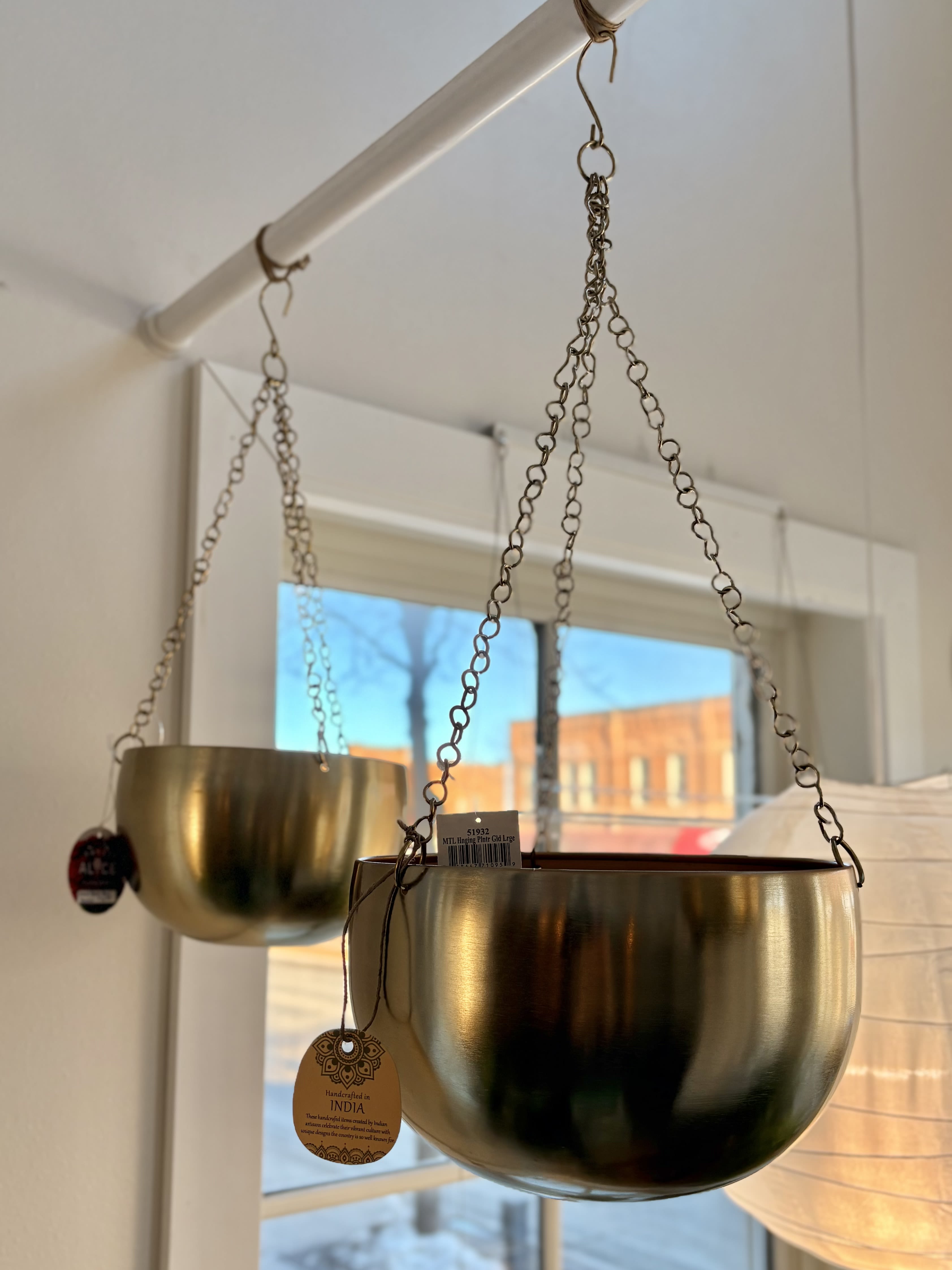 Two gold hanging planters suspended from chains indoors