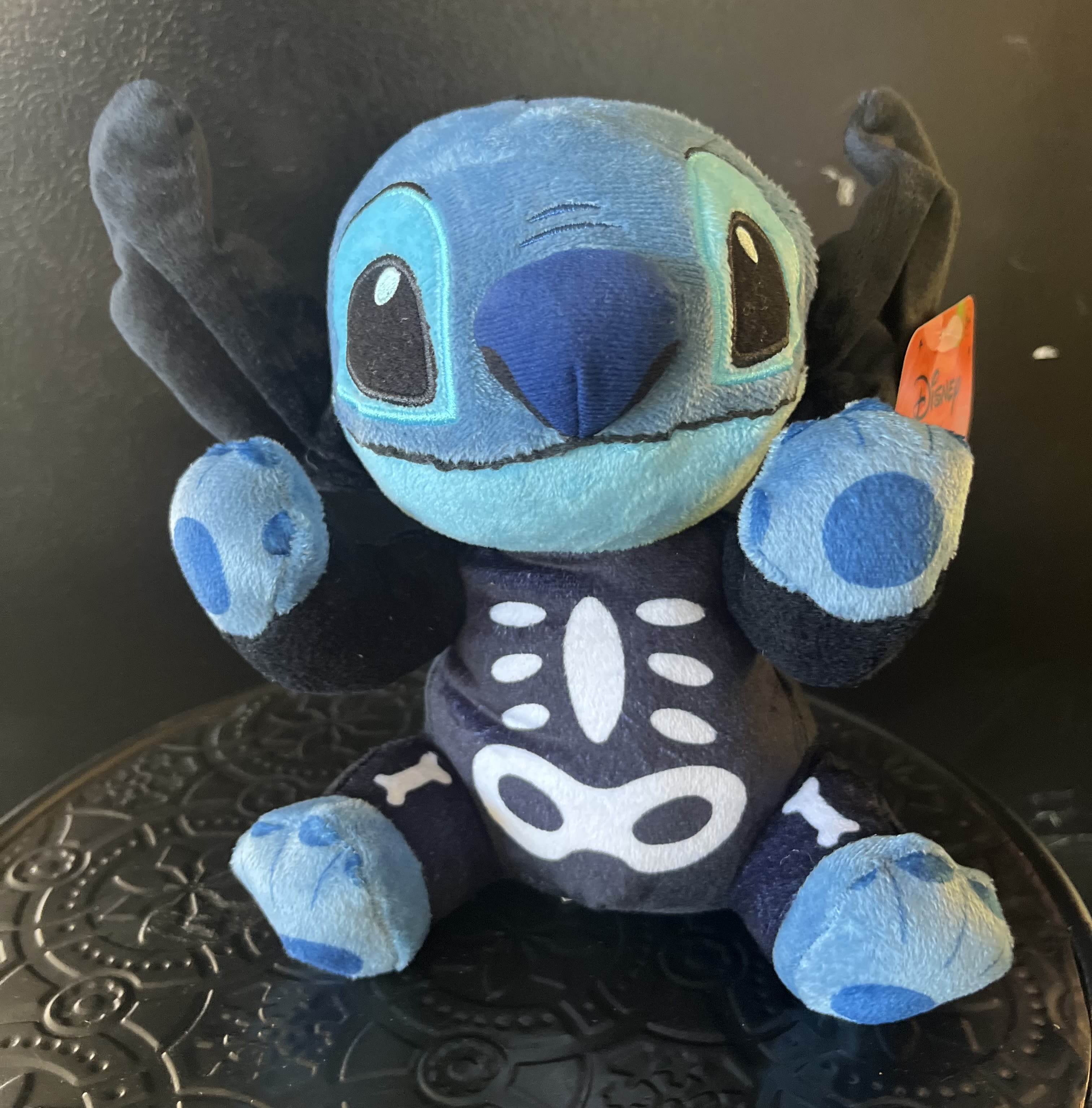 Blue Stitch plush toy with raised arms and a black skeleton costume