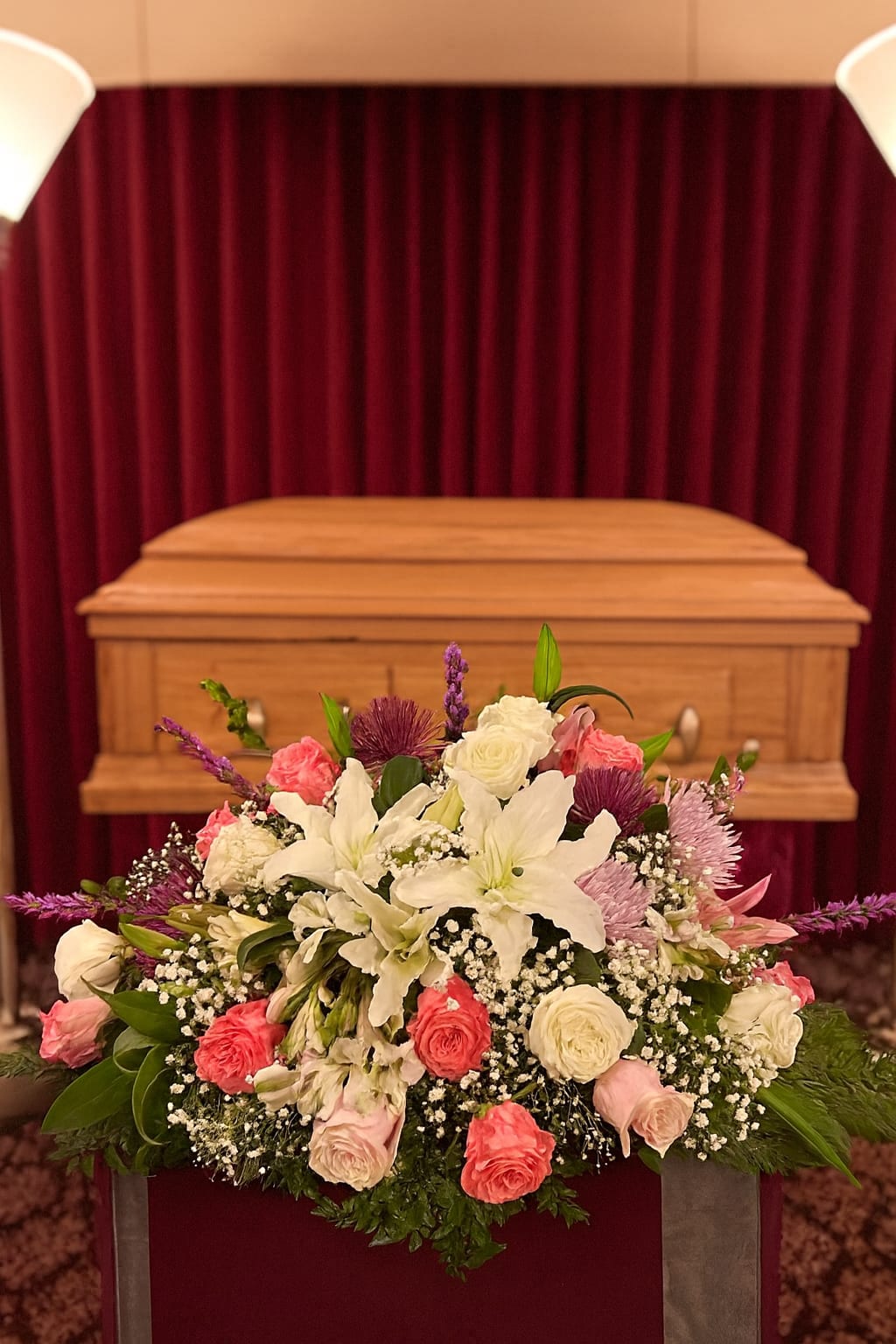 White lilies and pink roses arranged in front of a casket