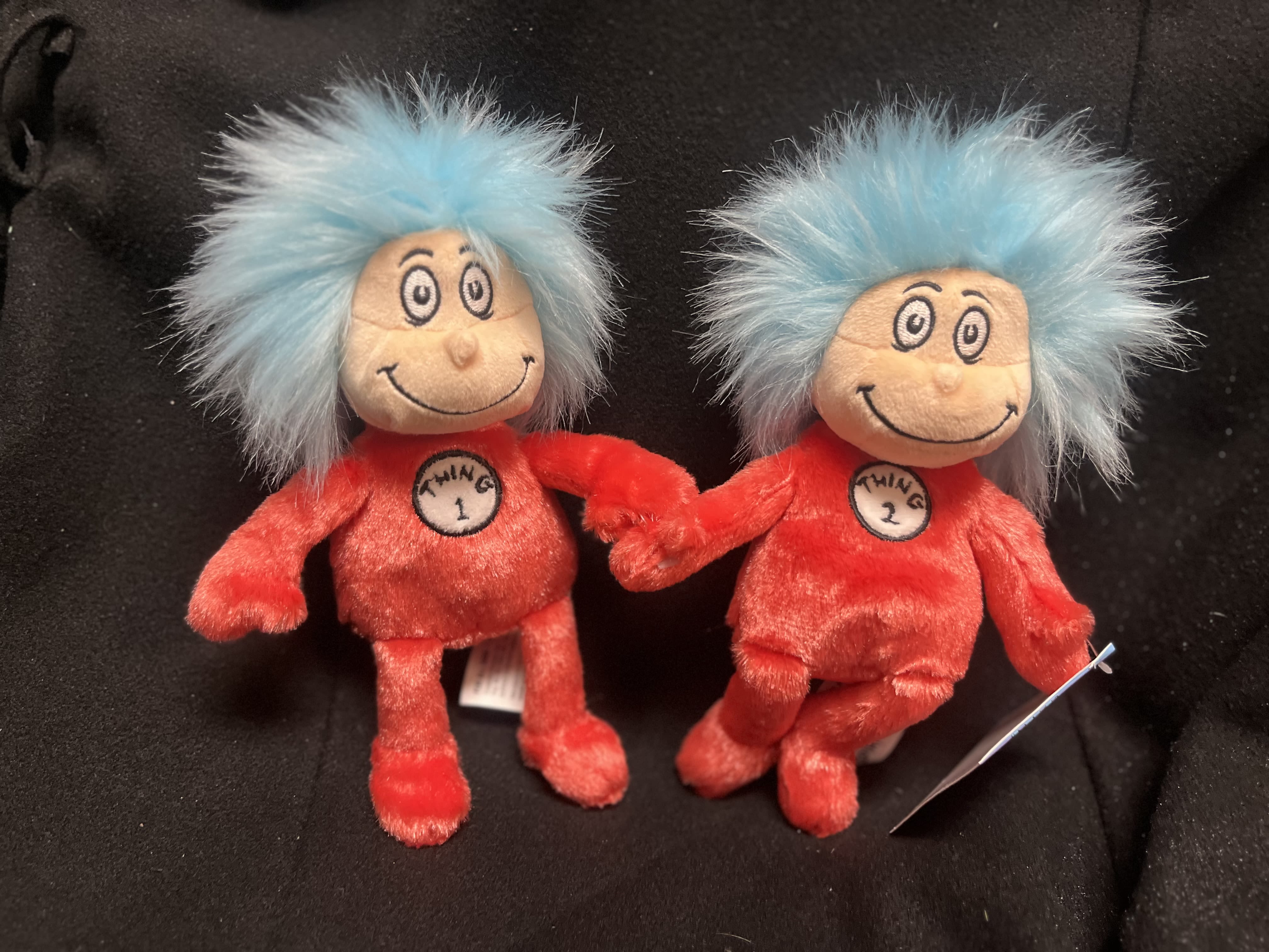 Two small plush characters with blue hair and red outfits sitting together