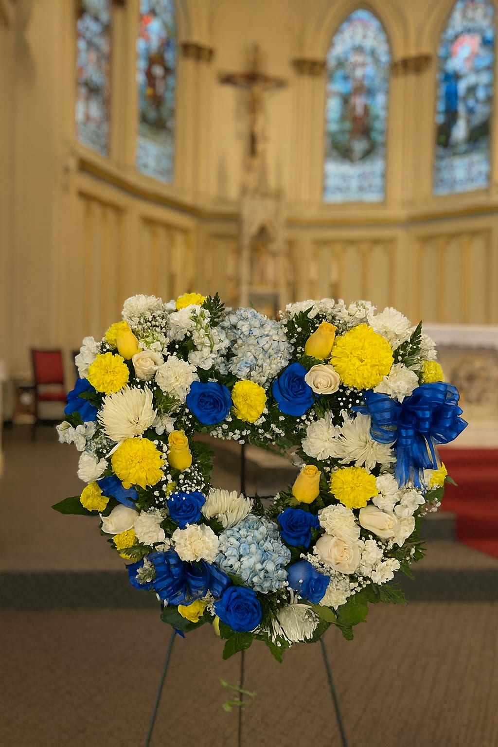 Heart-shaped floral wreath with blue, yellow, and white flowers