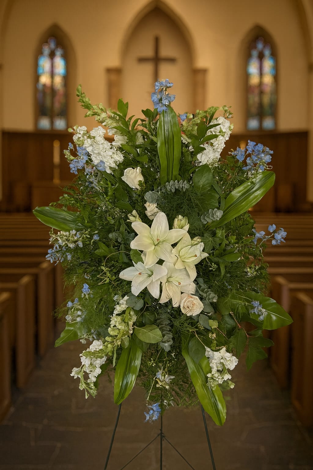 Large floral standing spray with white lilies and blue accents