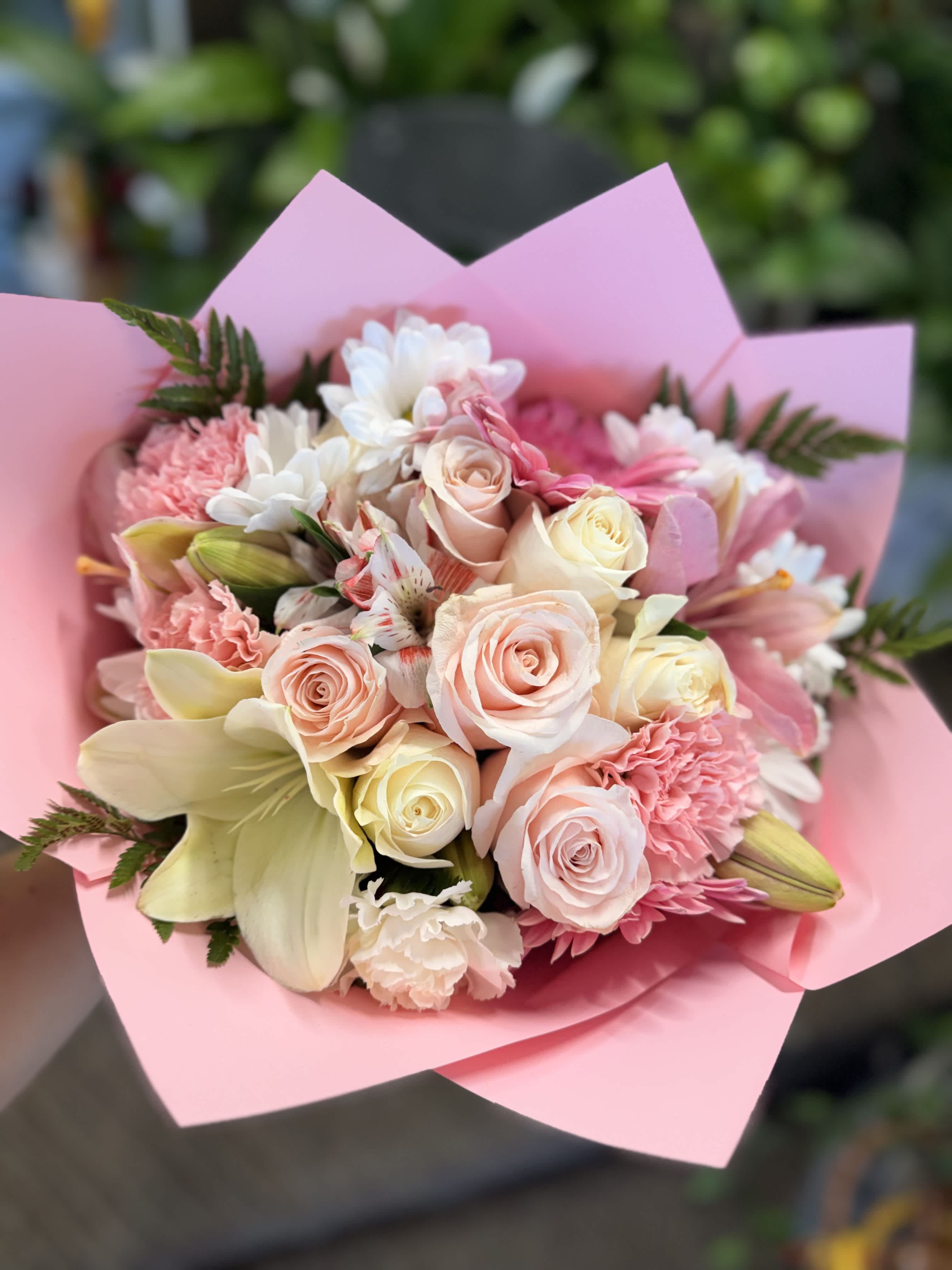 Pink and cream bouquet with roses, lilies, and carnations wrapped in pink paper
