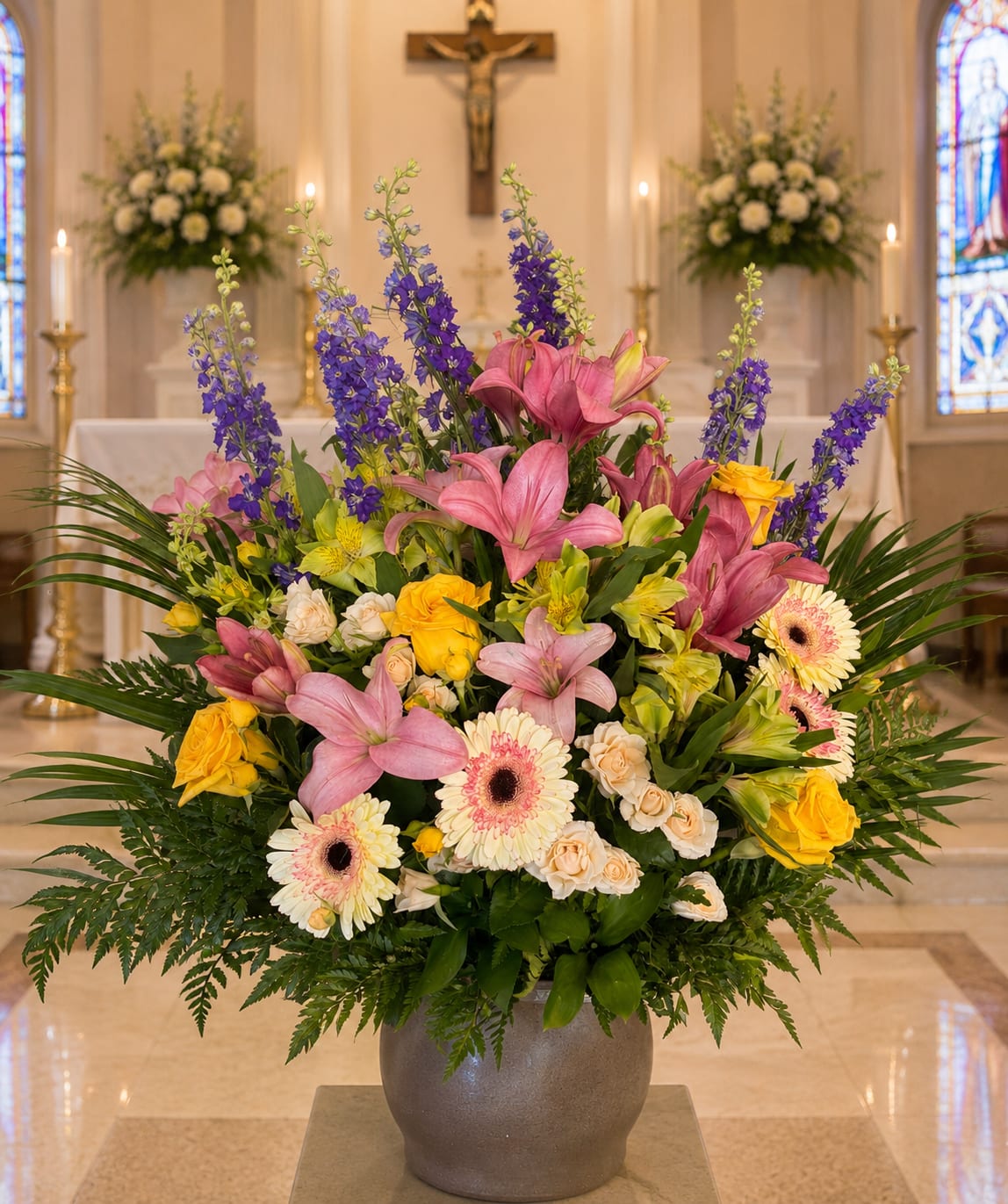Large mixed floral arrangement in a gray vase with pink lilies and yellow roses