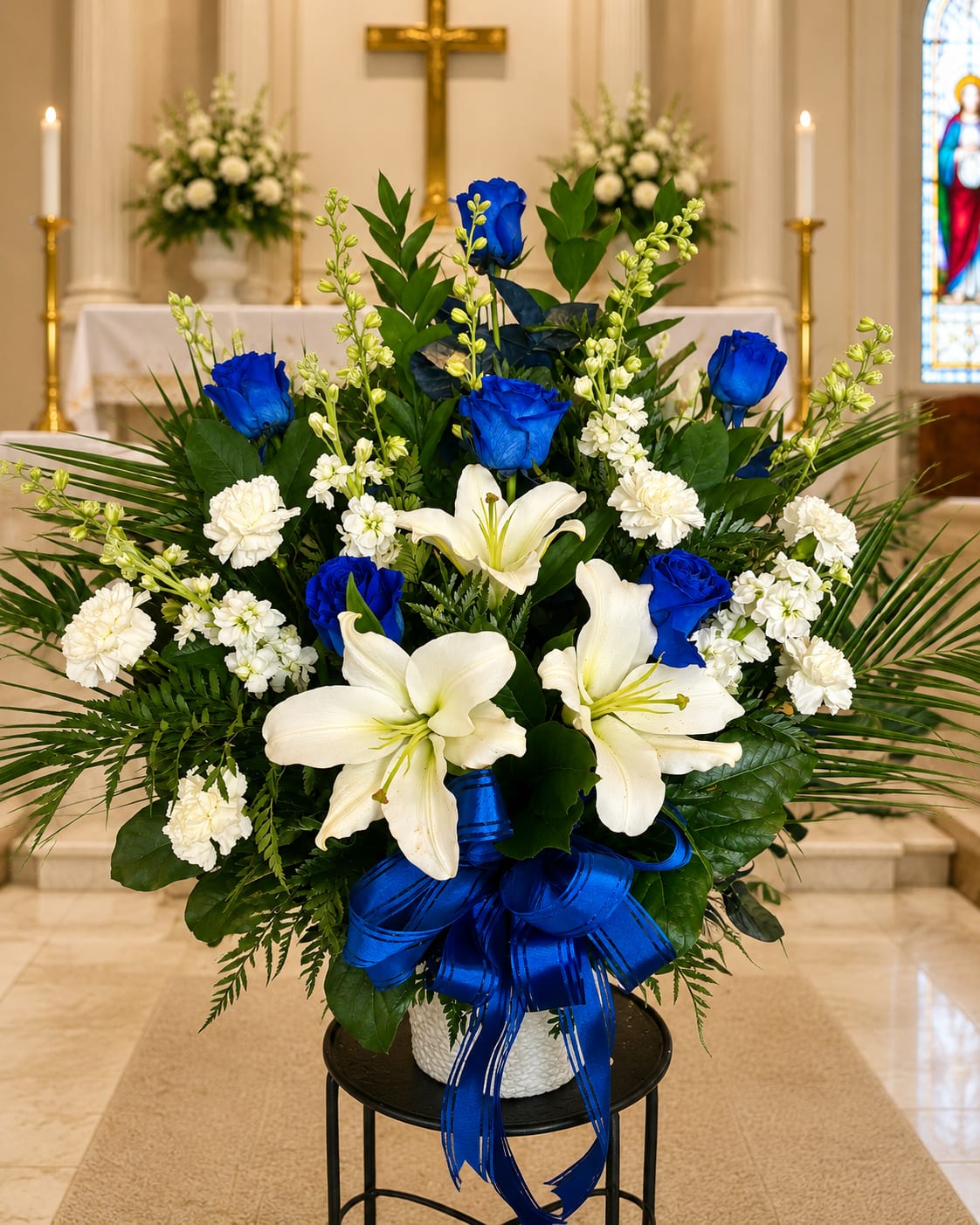 White lilies and blue roses in a vase with a blue ribbon