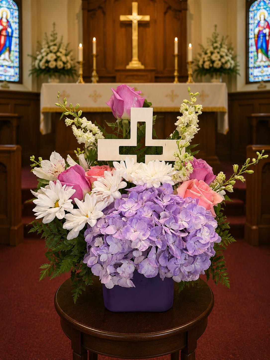 Pastel floral arrangement with a white cross in a purple vase