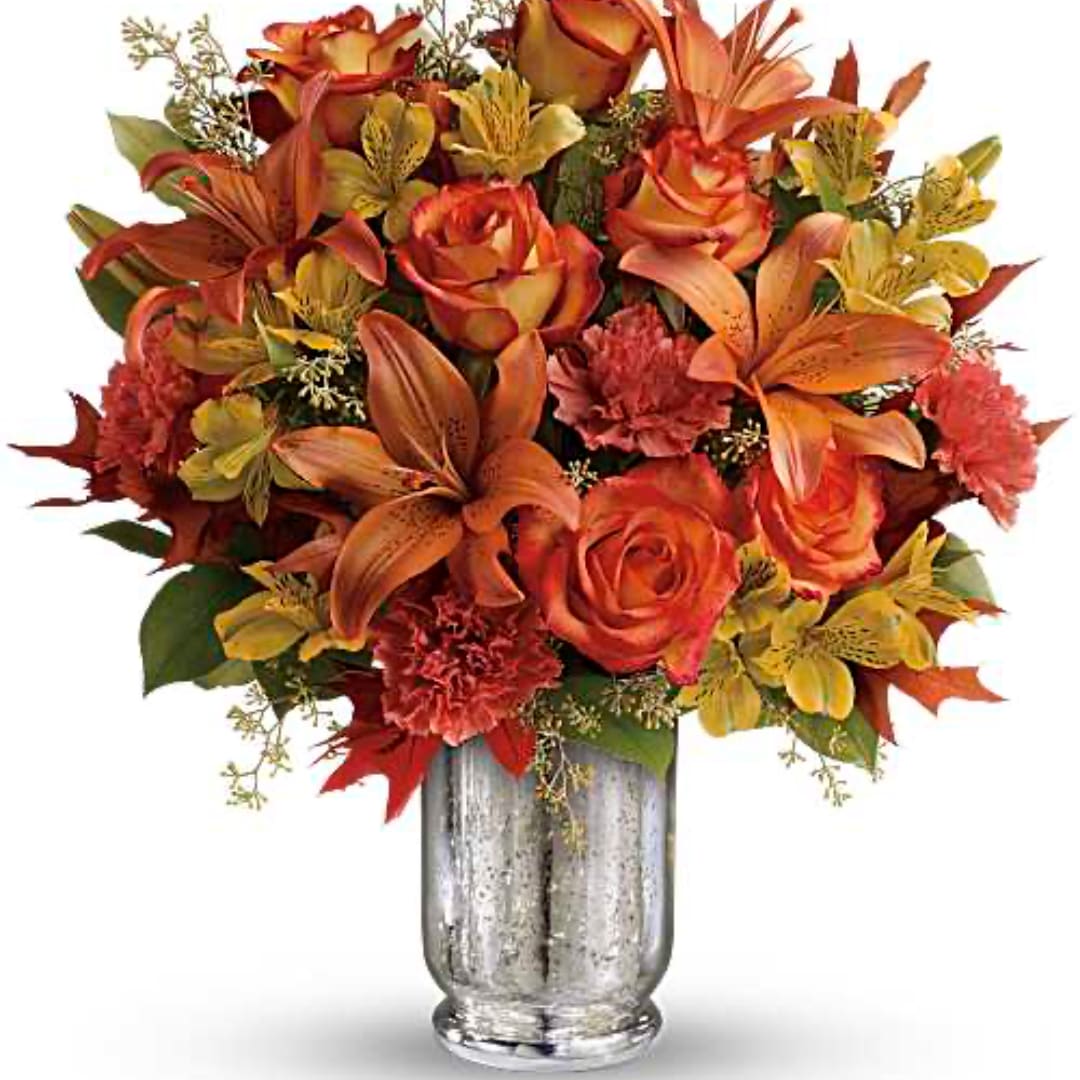 Orange and red floral arrangement in a silver vase