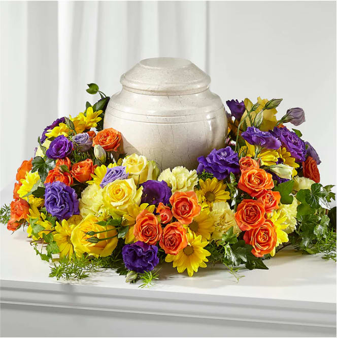 Colorful floral urn surround with roses and daisies around a cream urn