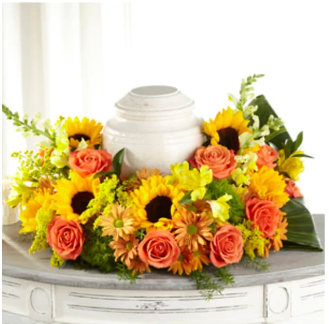 Sunflower and rose arrangement around a white urn