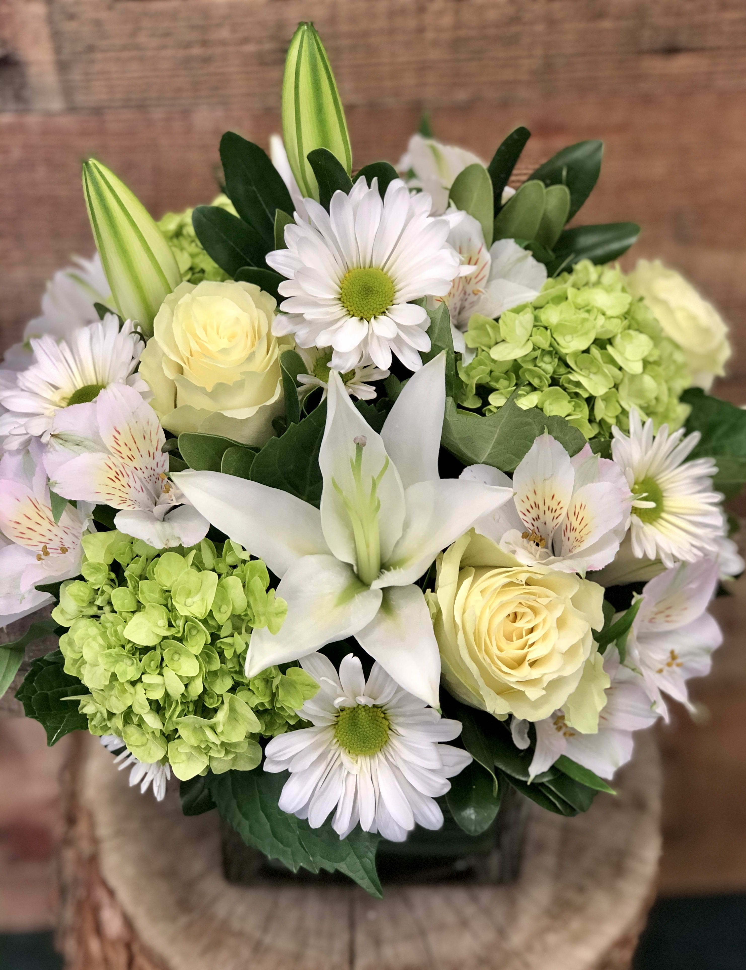Bouquet of white lilies, pale yellow roses, and daisies with green hydrangea