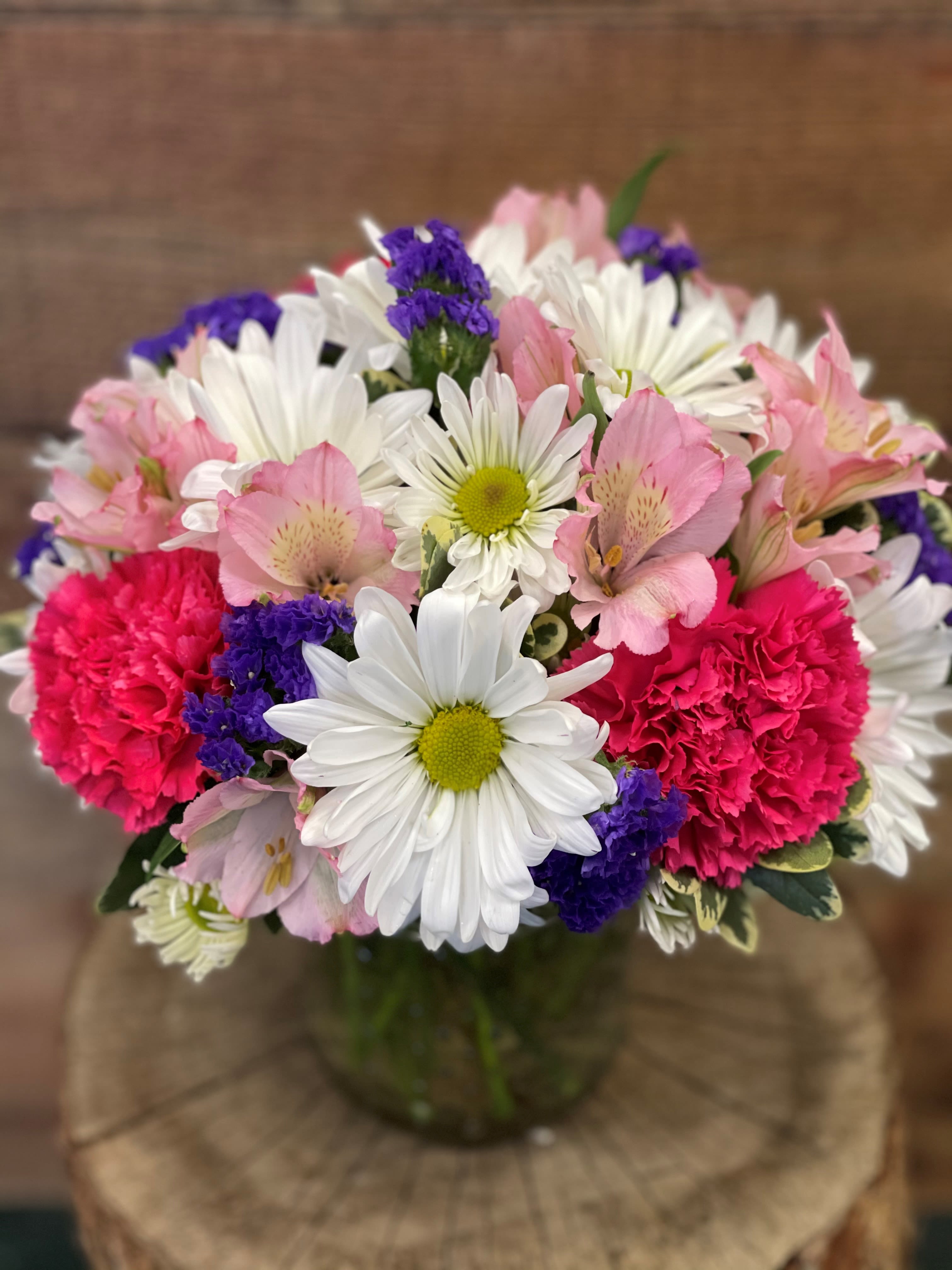 Bouquet of pink and white flowers with purple accents in a glass vase
