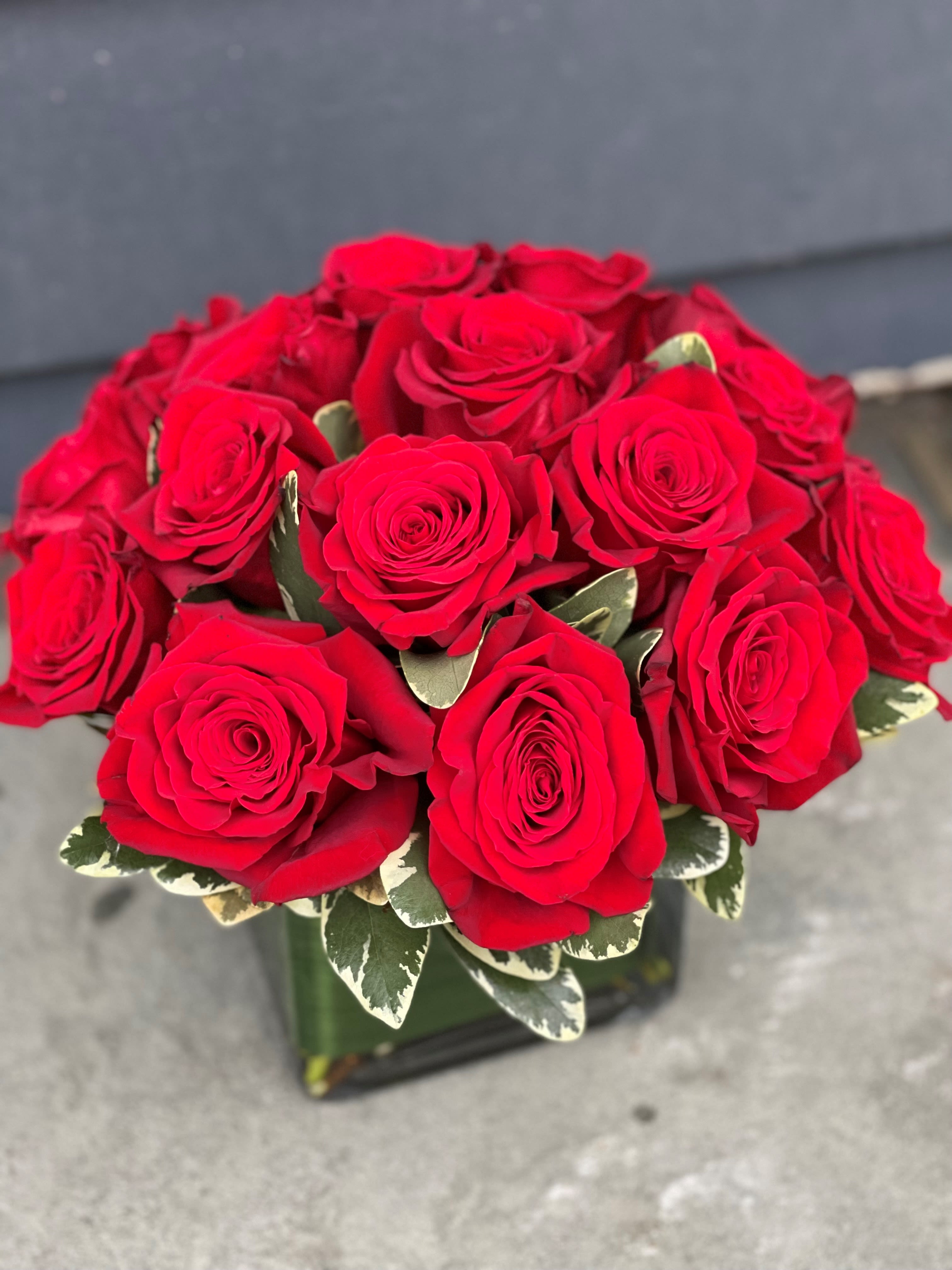 Bouquet of red roses with variegated leaves in a glass vase