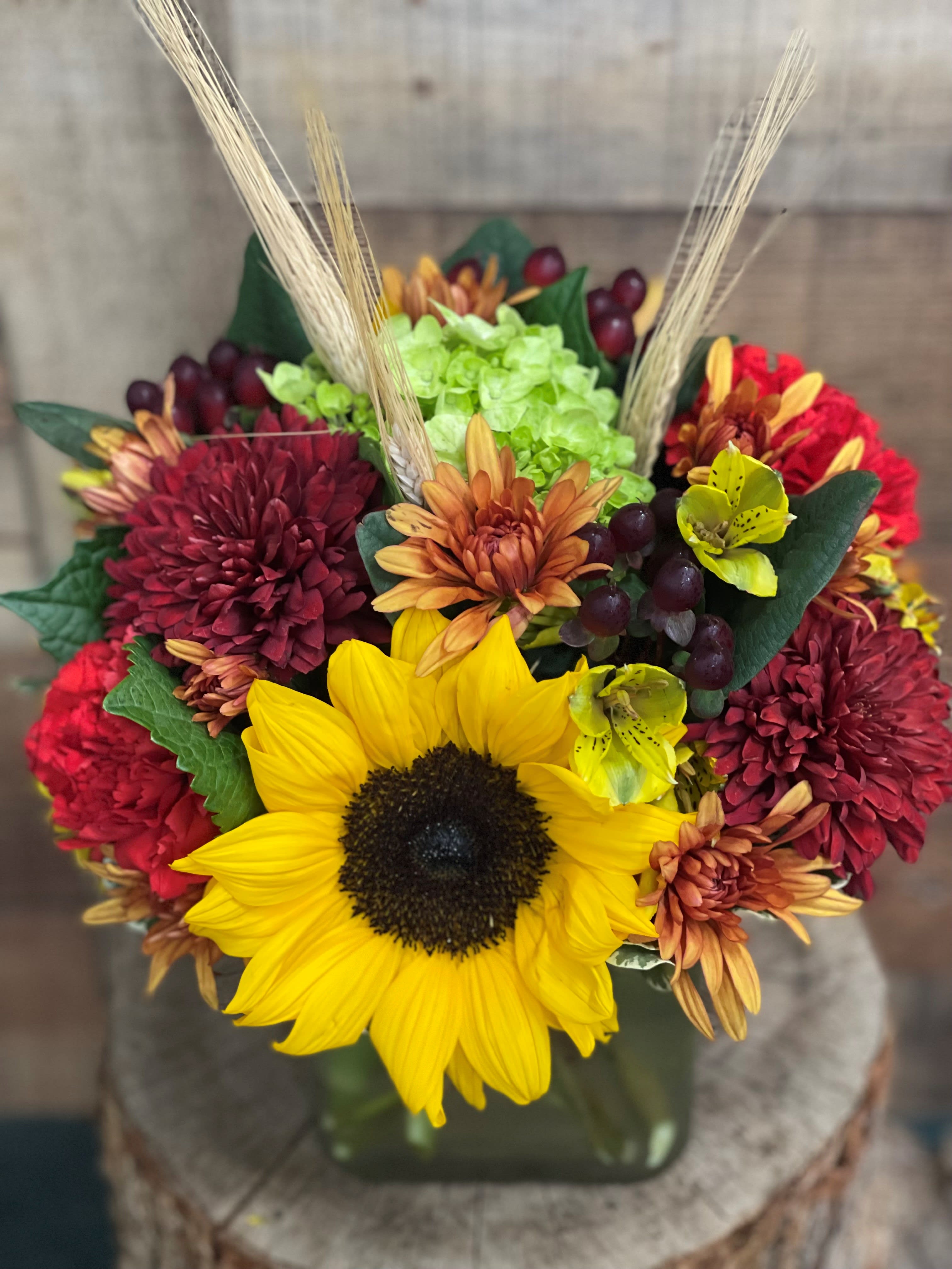 Burst of Fall - All the colors you would expect from a fall arrangement designed in a compact cube accented with berries and wheat.