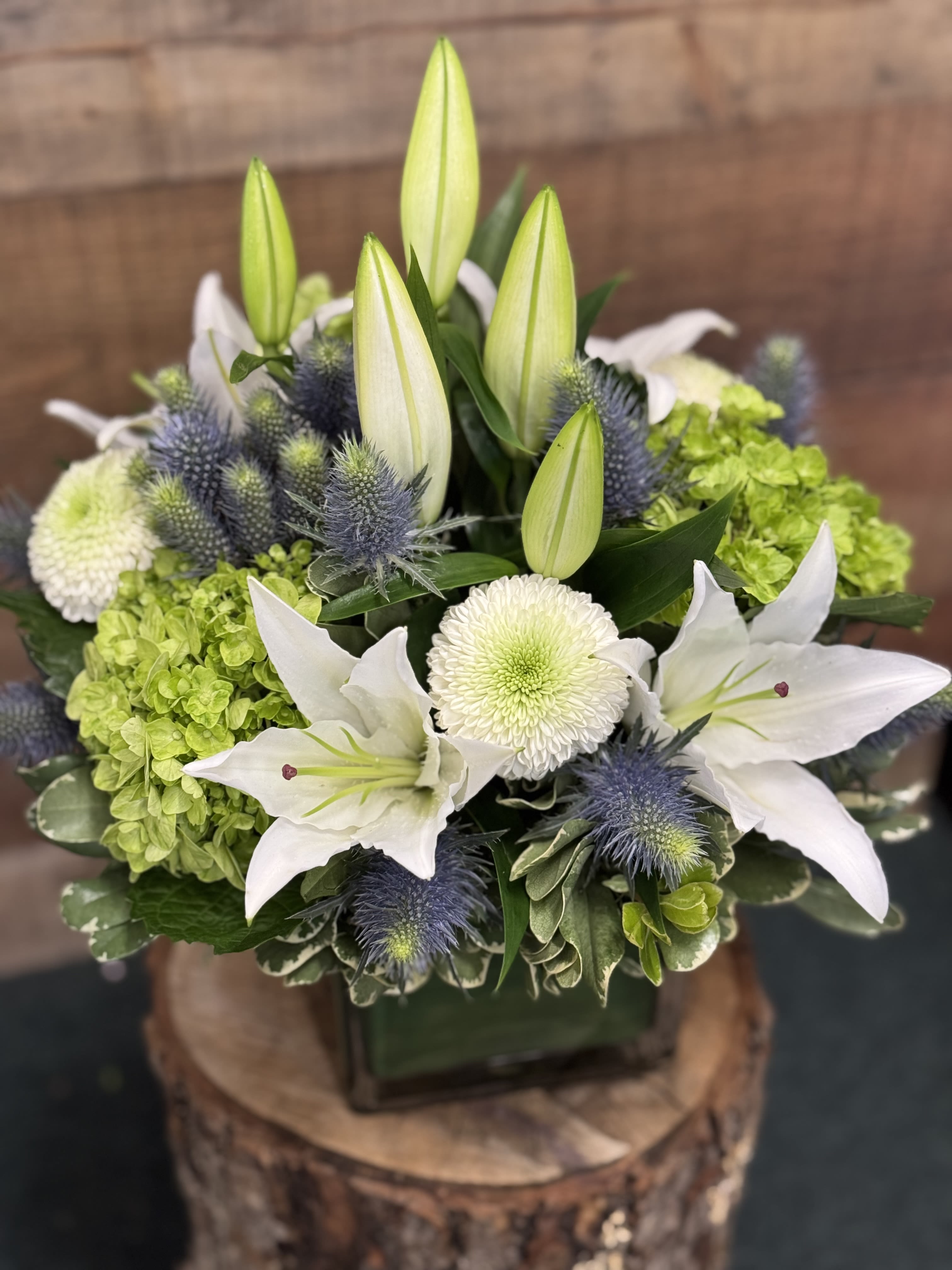 White lilies and green hydrangeas arranged in a square vase