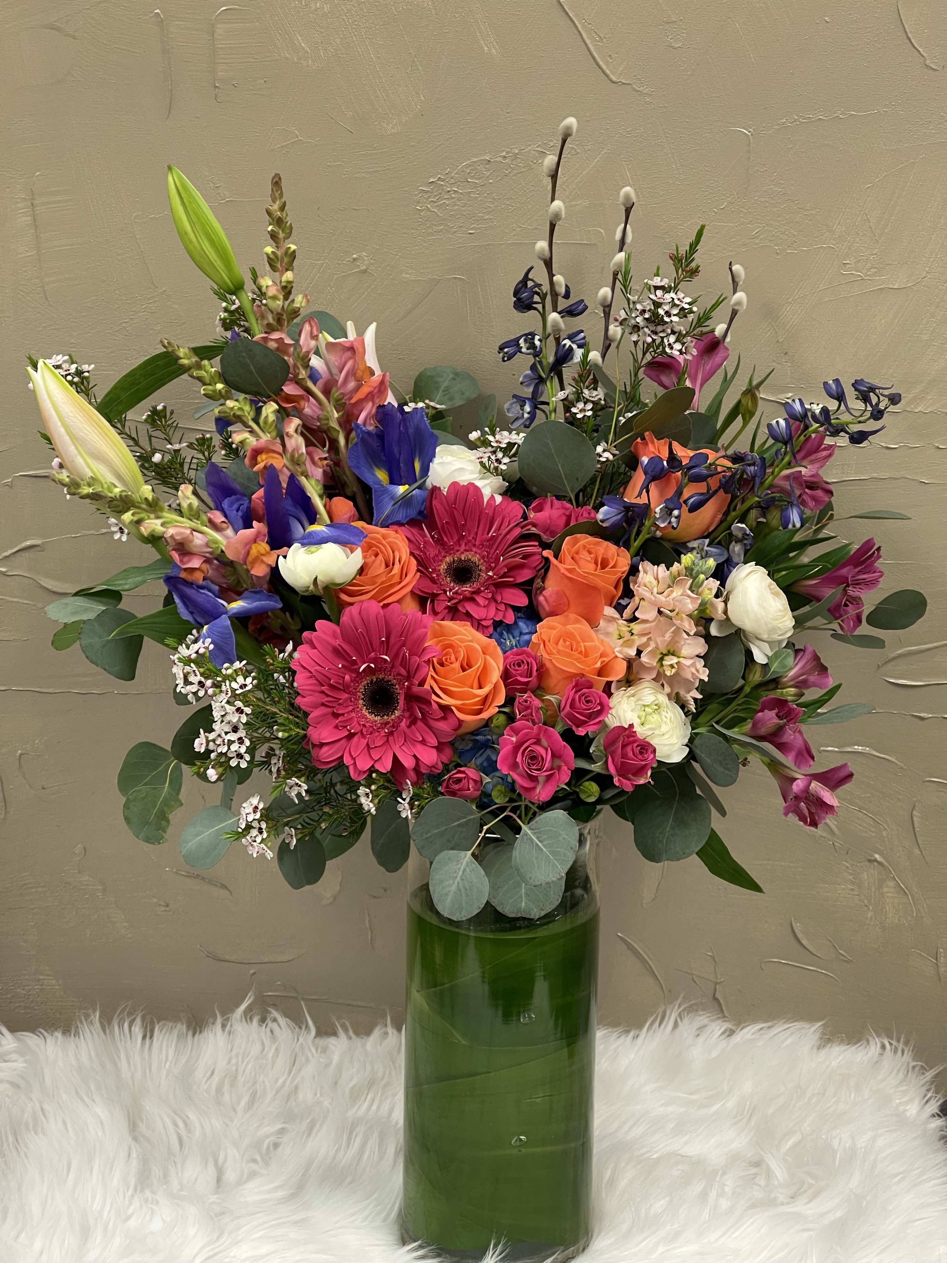 Colorful mixed bouquet in a tall green glass vase