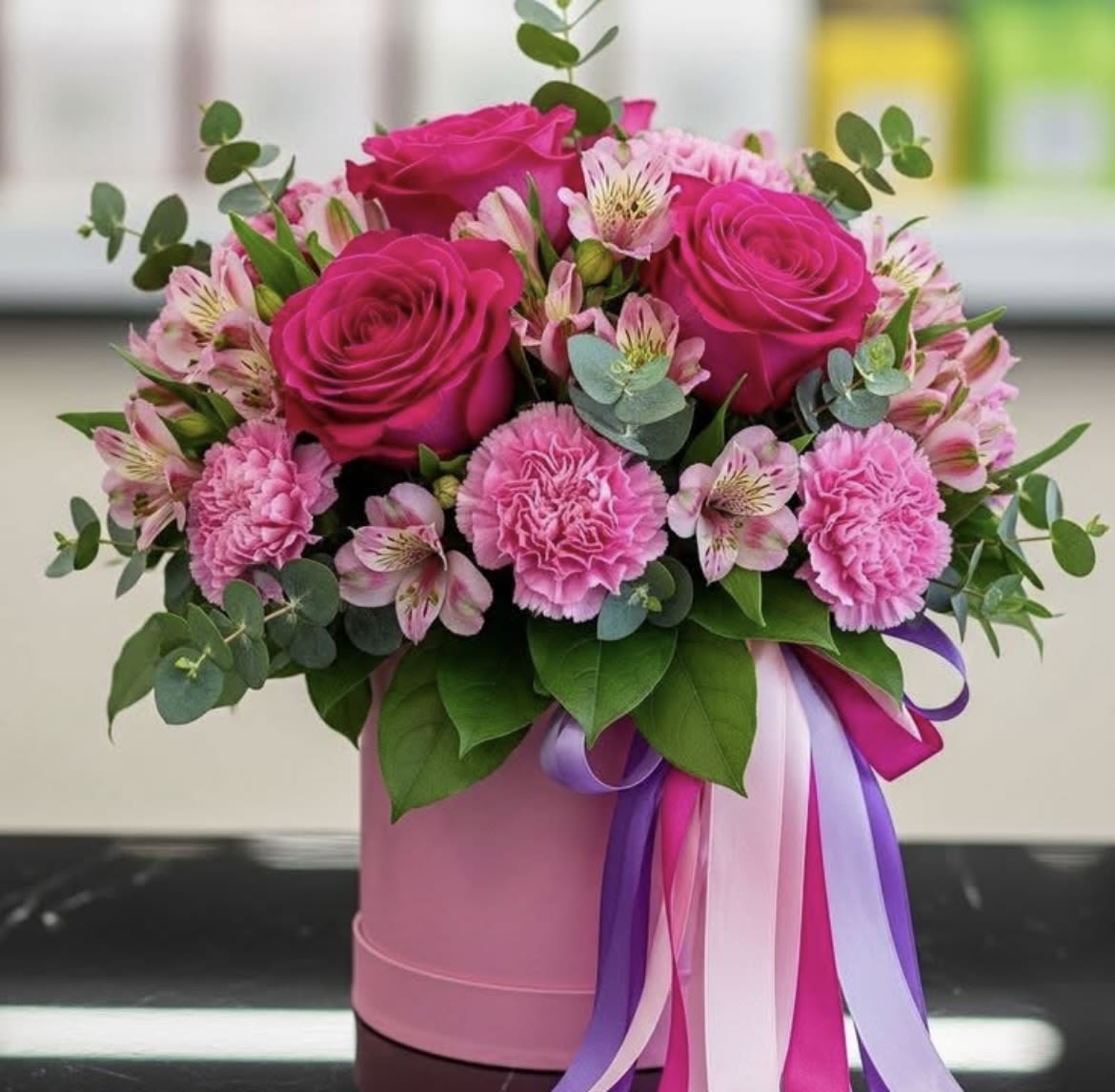 Bloom of Love - Bright pink roses, ruffled carnations and pink alstroemeria in a pink box with pink, white and purple ribbons.
