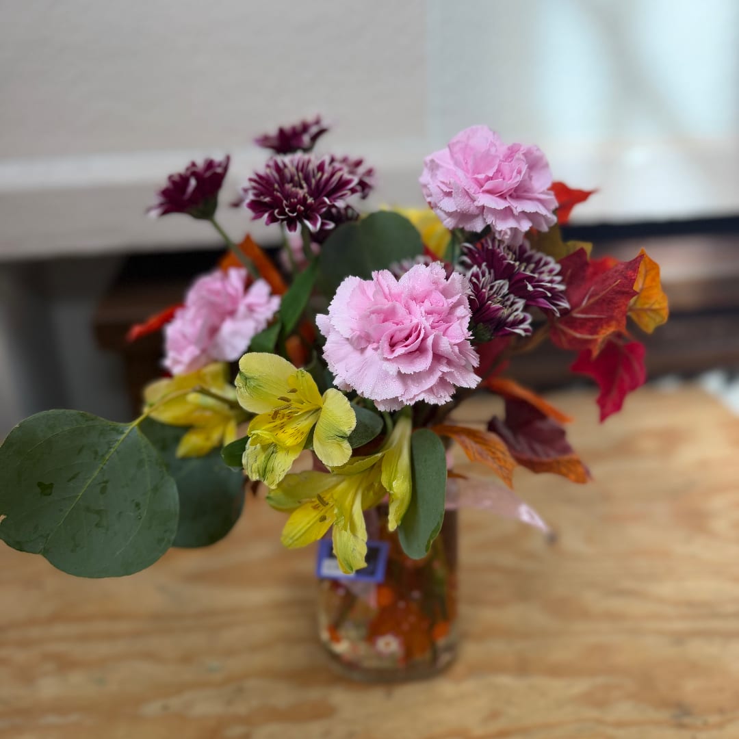 Mixed bouquet of pink and yellow flowers in a glass vase