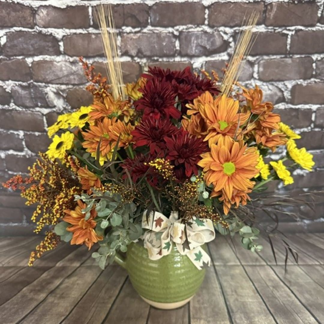 Fall bouquet of orange, yellow, and burgundy flowers in a green vase