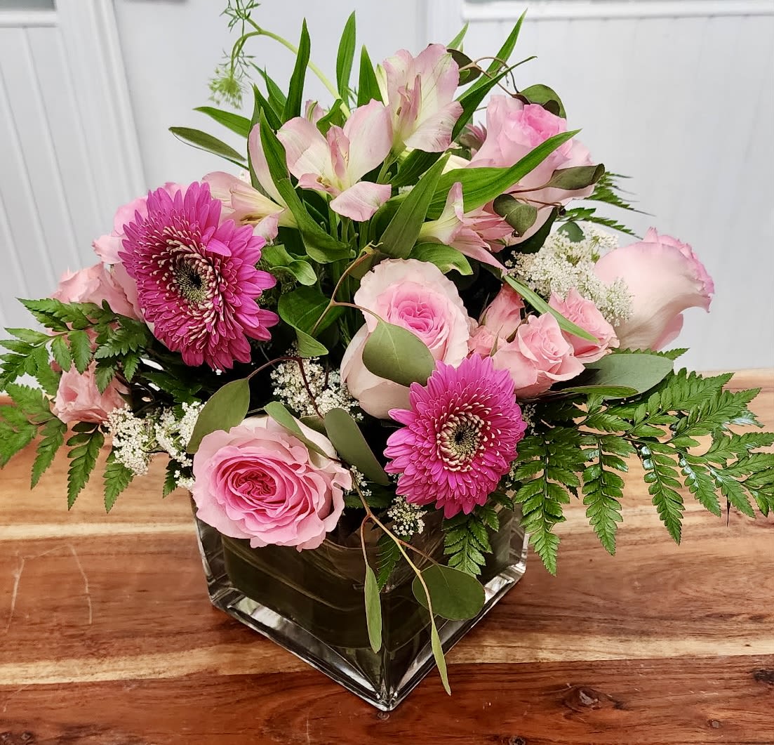 Pink roses and gerbera daisies in a square glass vase
