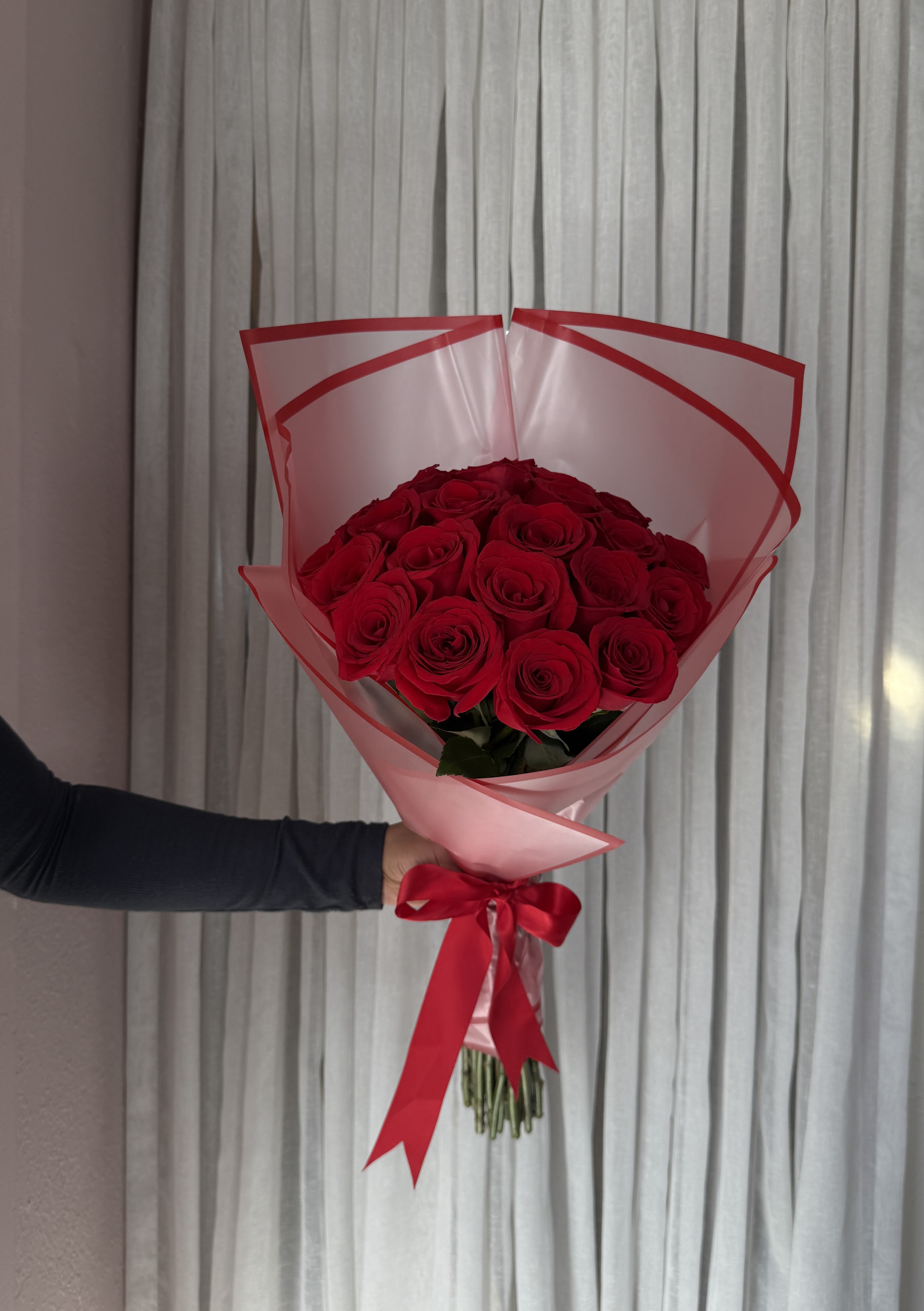 Bouquet of red roses wrapped in pink paper with a red ribbon