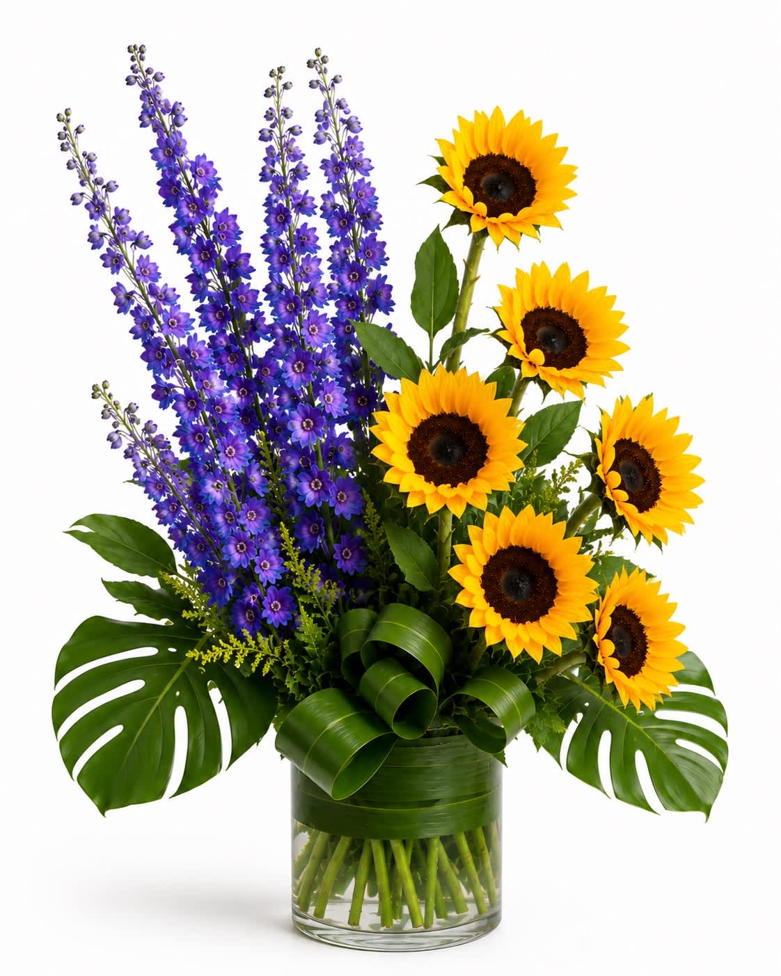 Sunflowers and purple delphinium in a clear glass vase