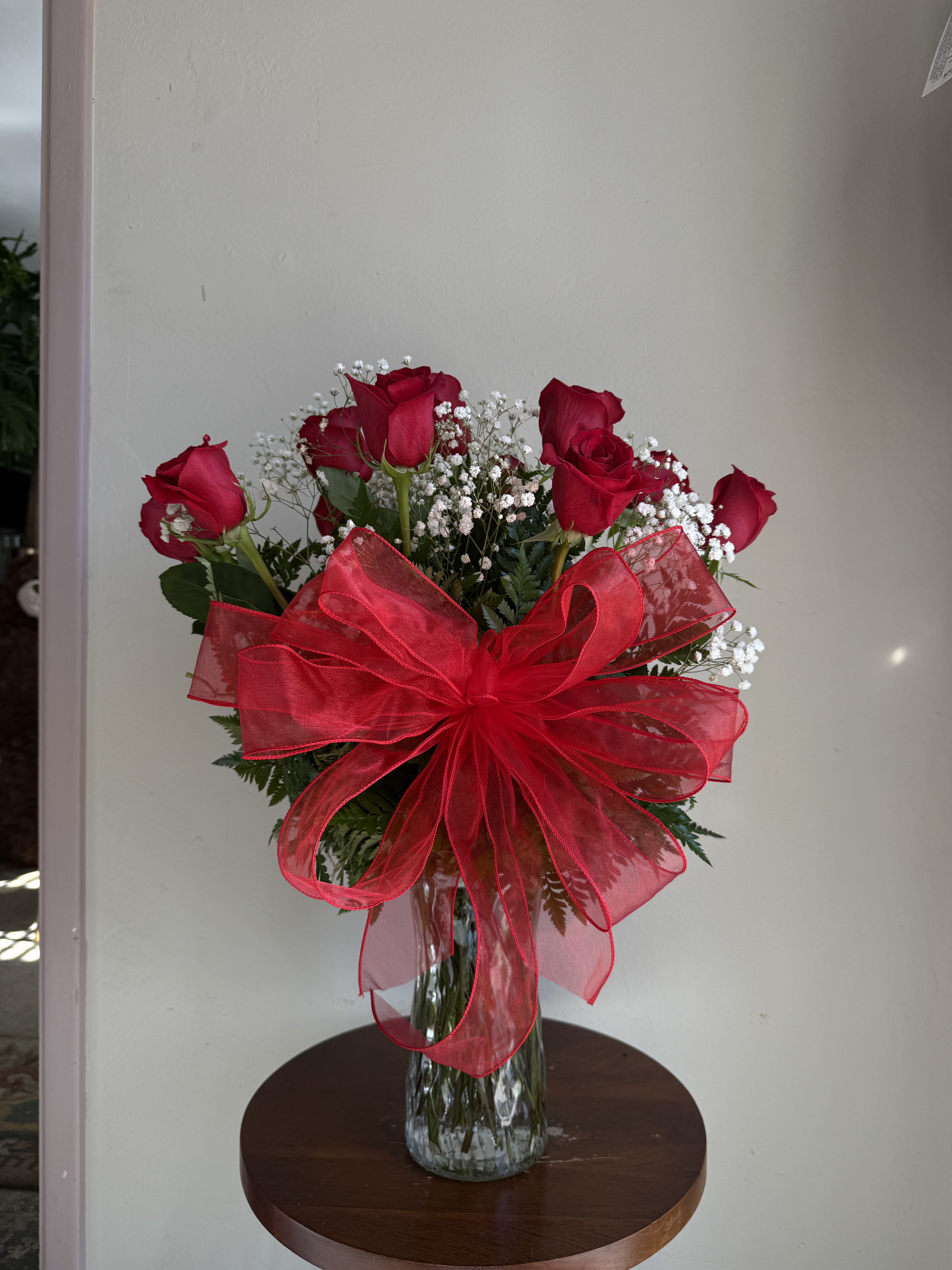 Red roses in a glass vase with a large red bow