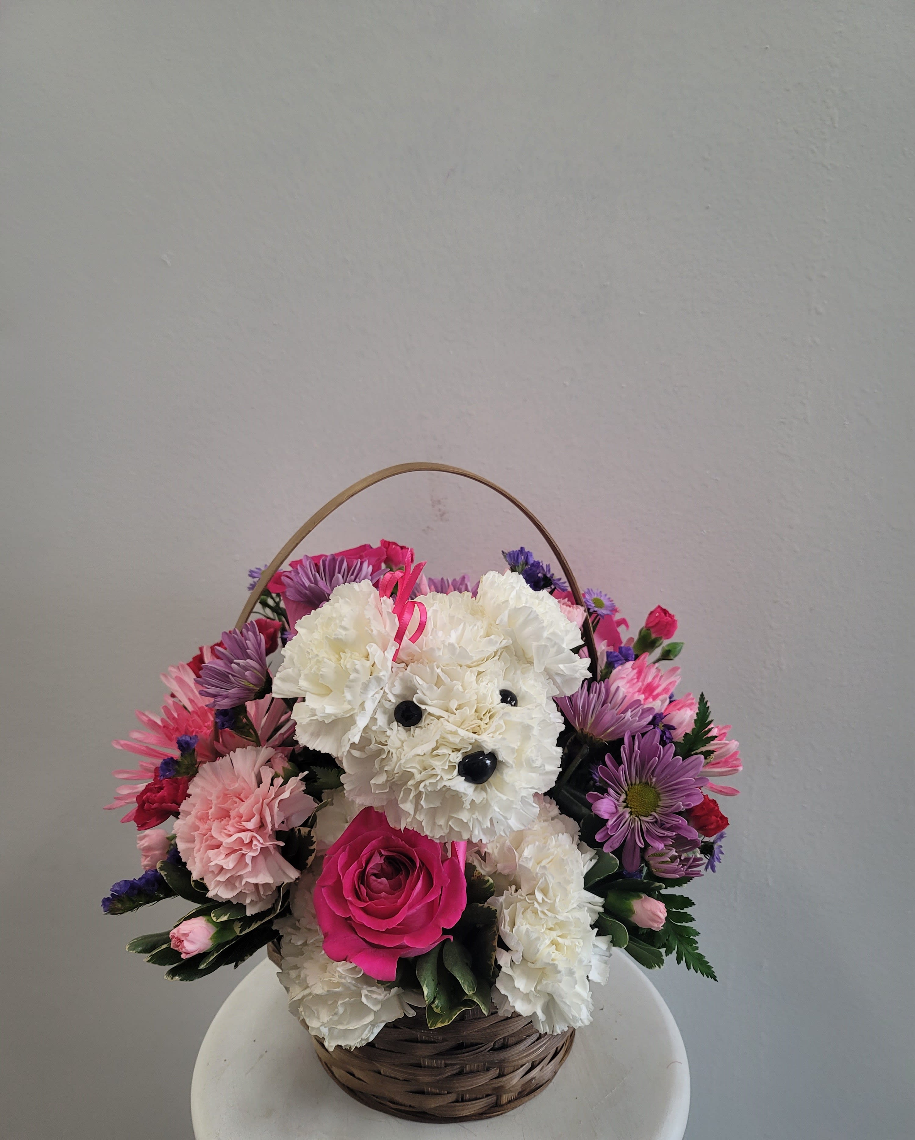 Basket arrangement with a teddy bear made of white carnations and pink flowers