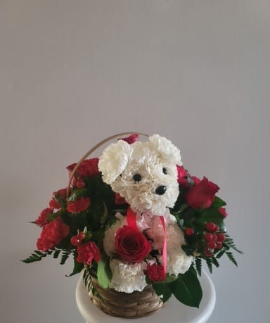 Basket arrangement with a white plush dog and red roses