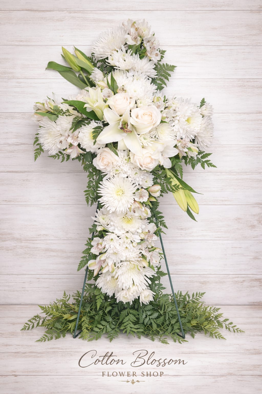 White floral cross arrangement with lilies, roses, and chrysanthemums