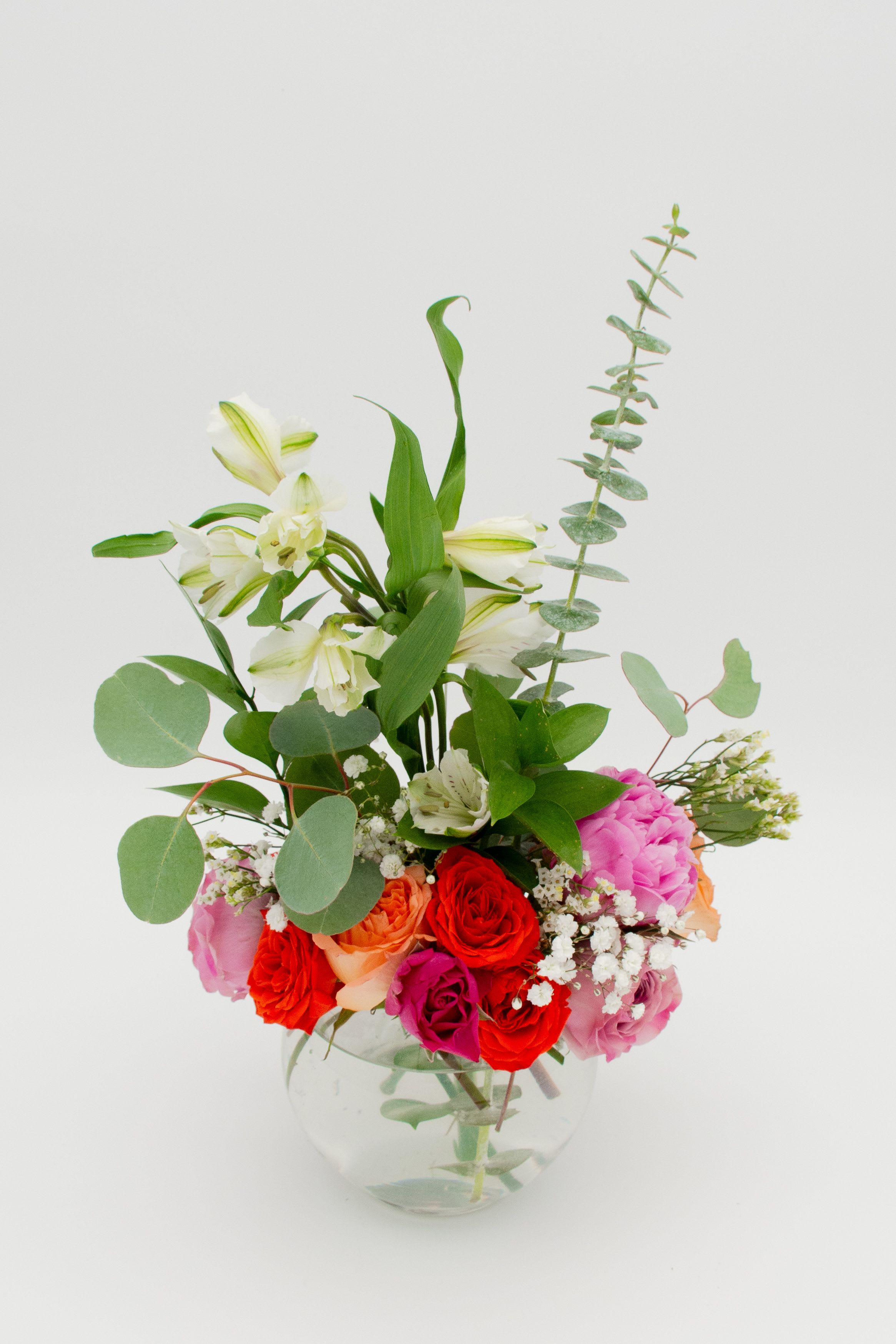 Mixed bouquet of roses and white lilies in a clear glass vase