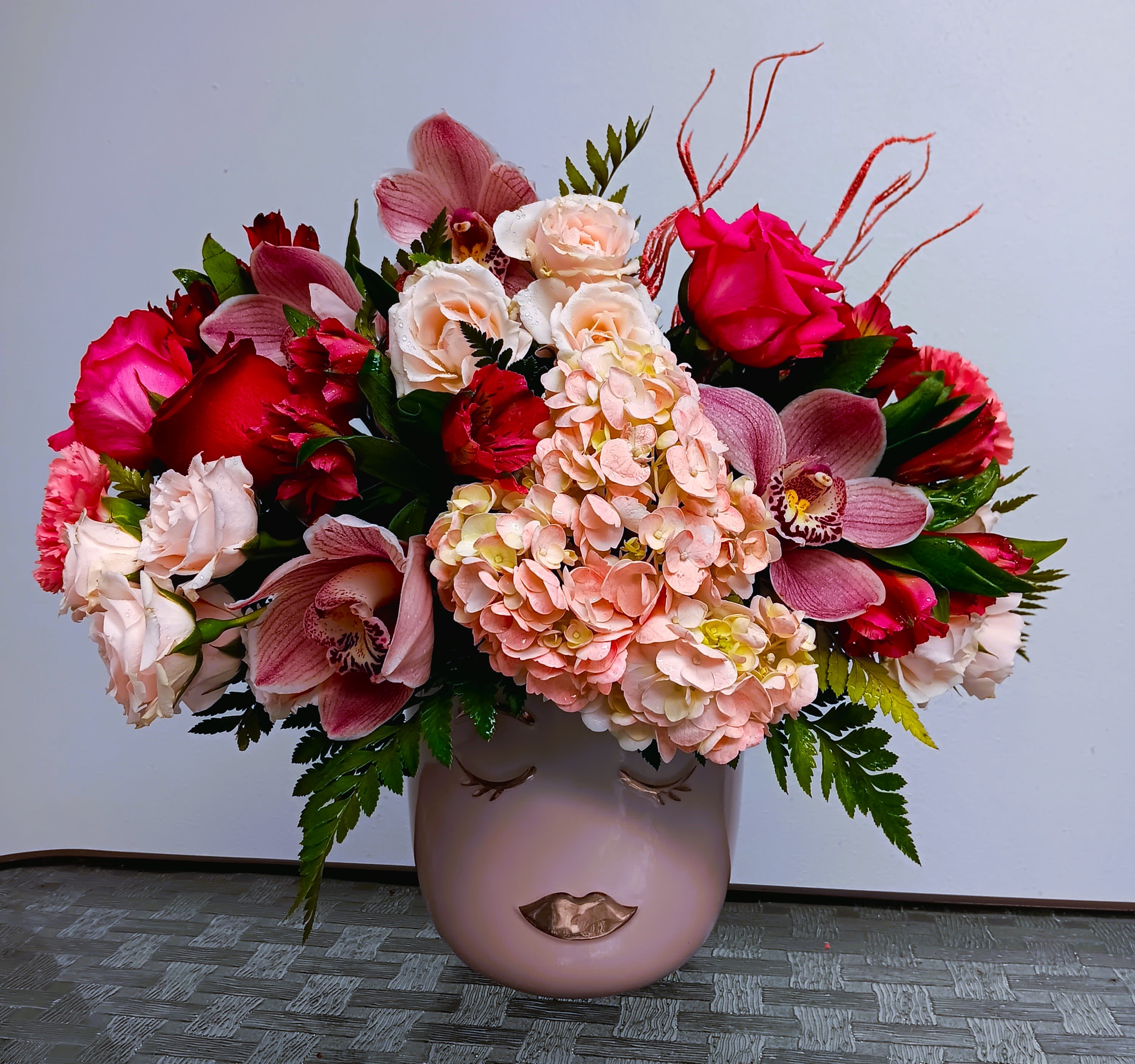 Pink and red mixed flower arrangement in a blush vase
