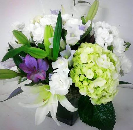 Bouquet of white and purple flowers with green lilies in a black vase