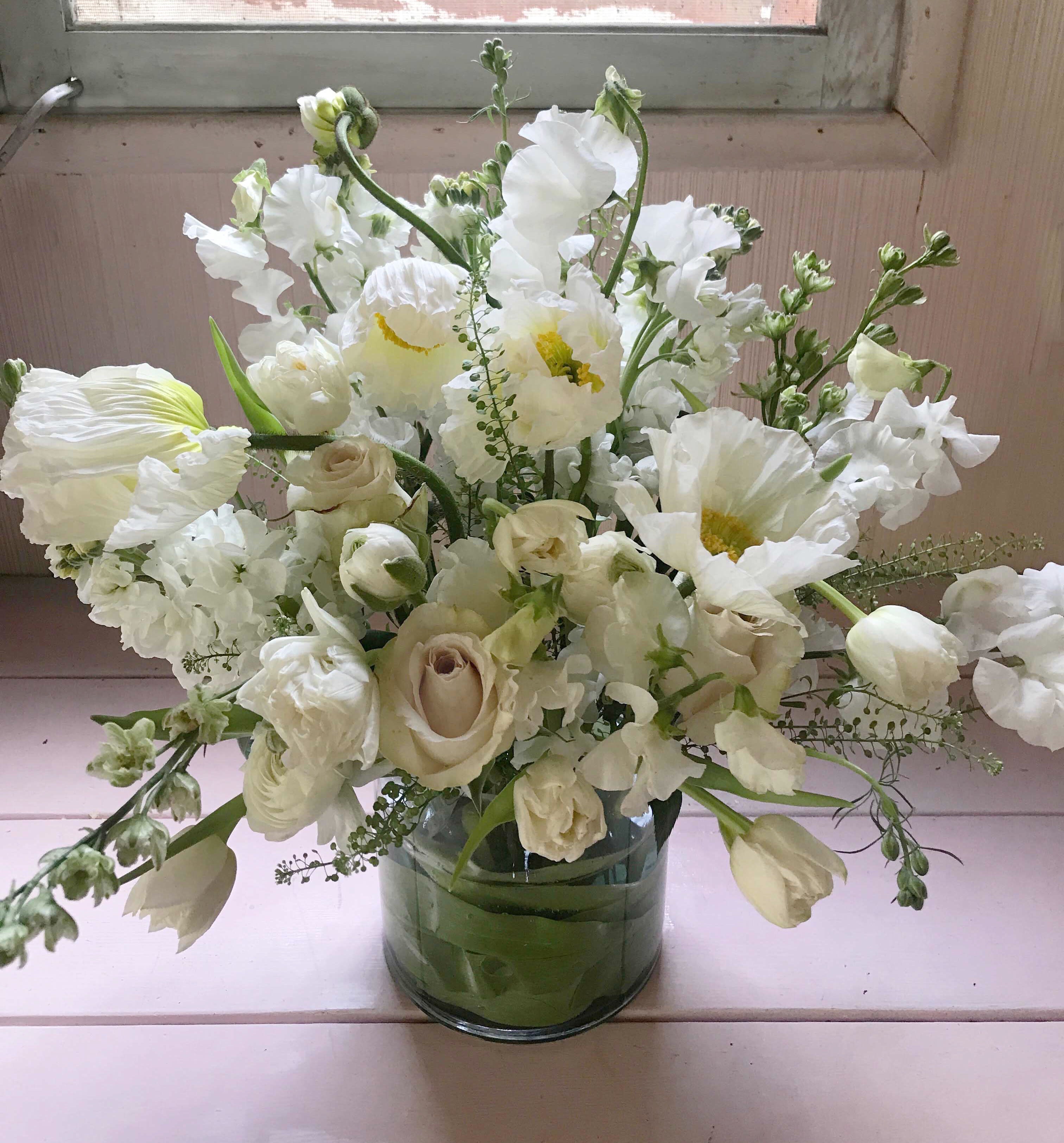 Karen Blixen arrangement - Named after the Danish heroine, author and storyteller Karen Blien (Isak Dinesen who loved fresh flowers in her home in Denmark and at her farm in Africa. Fresh, clean, elegant, white arrangement full of beauty. Hydrangeas, poppies, tulips, roses, sweetpeas and delphiniums, all in white. When in season poppies will be used, when not, big ranunculus will adorn this dreamy poetic arrangement that comes in a clear vase (6 by 6 inches).  Blomst LA only uses fresh, high quality flowers, all carefully selected every day to fit your flower order. You can see the design made for happy customer on images shown, at different times of year (with a slight variation on the flowers). We offer a personal hand delivery by our own delivery staff and guarantee the flowers will look perfect, when they arrive. We deliver in Glendale, Pasadena, Eagle Rock, Hollywood, Burbank, Beverly Hills - and everywhere else in Greater Los Angeles.