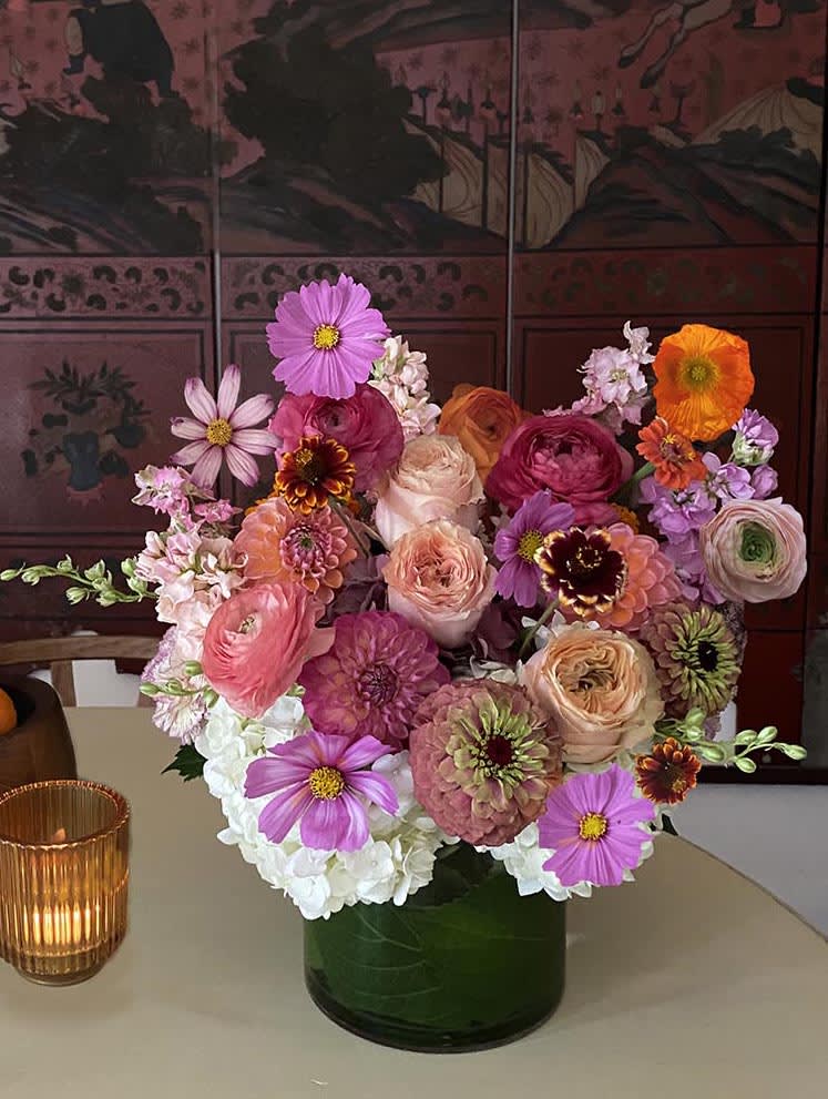 Mixed bouquet of pink, purple, orange, and white flowers in a dark vase