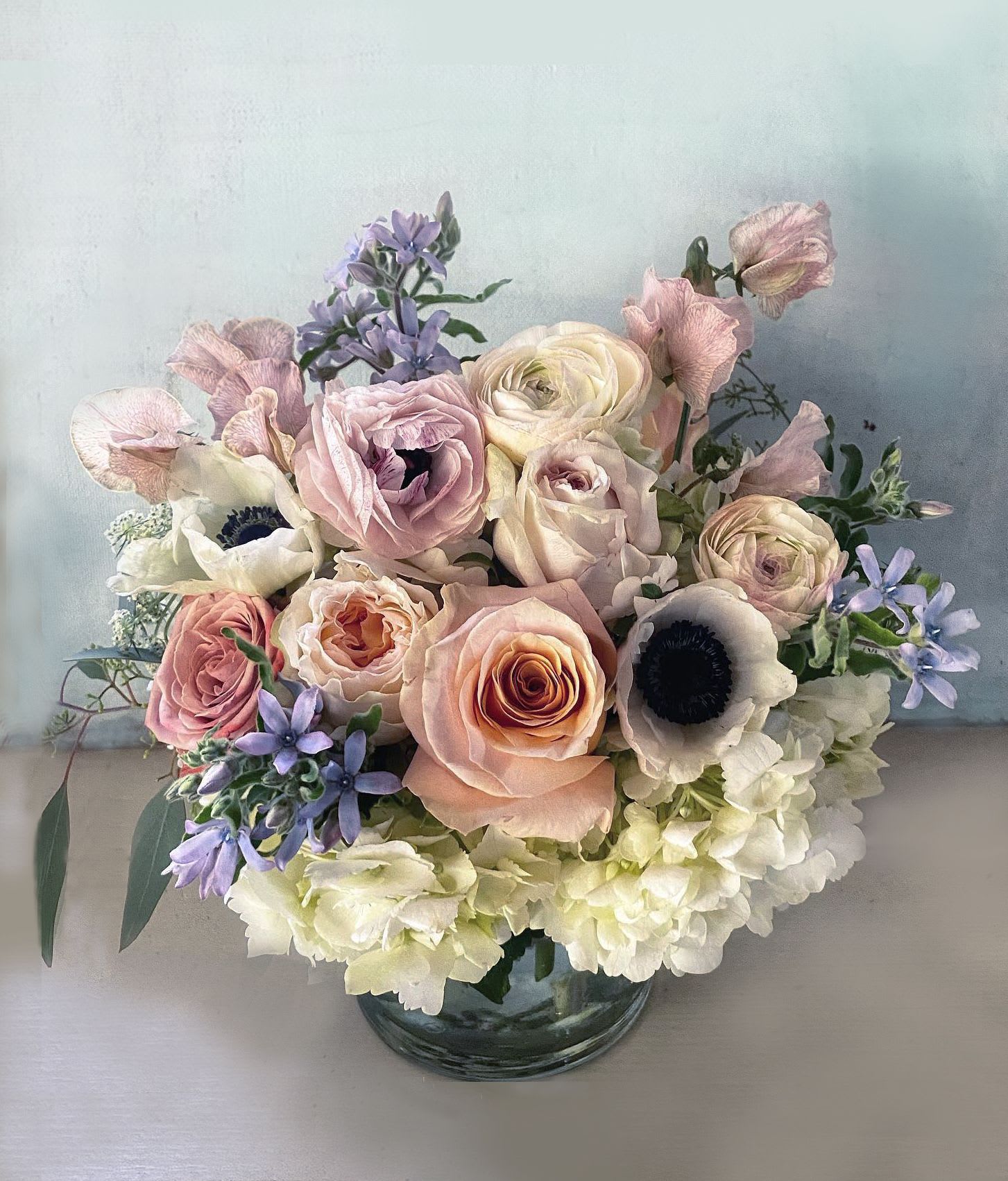 The Helga - Elegant, ethereal arrangement of breathtaking dusty blush, sandy, coral colors. in Norse mythology Helga means Divine Woman. This arrangement is perfect for all divine women, or men, and will make an impact on the eye. Roses, ranunculus, stock, delphniums, hand picked delightful pastel colored seasonal stems and light greens are the perfect combination in this classic arrangement. Blomst LA only uses fresh, high quality flowers, all carefully selected every day to fit your flower order. We offer a personal hand delivery by our own delivery staff and guarantee the flowers will look perfect, when they arrive.