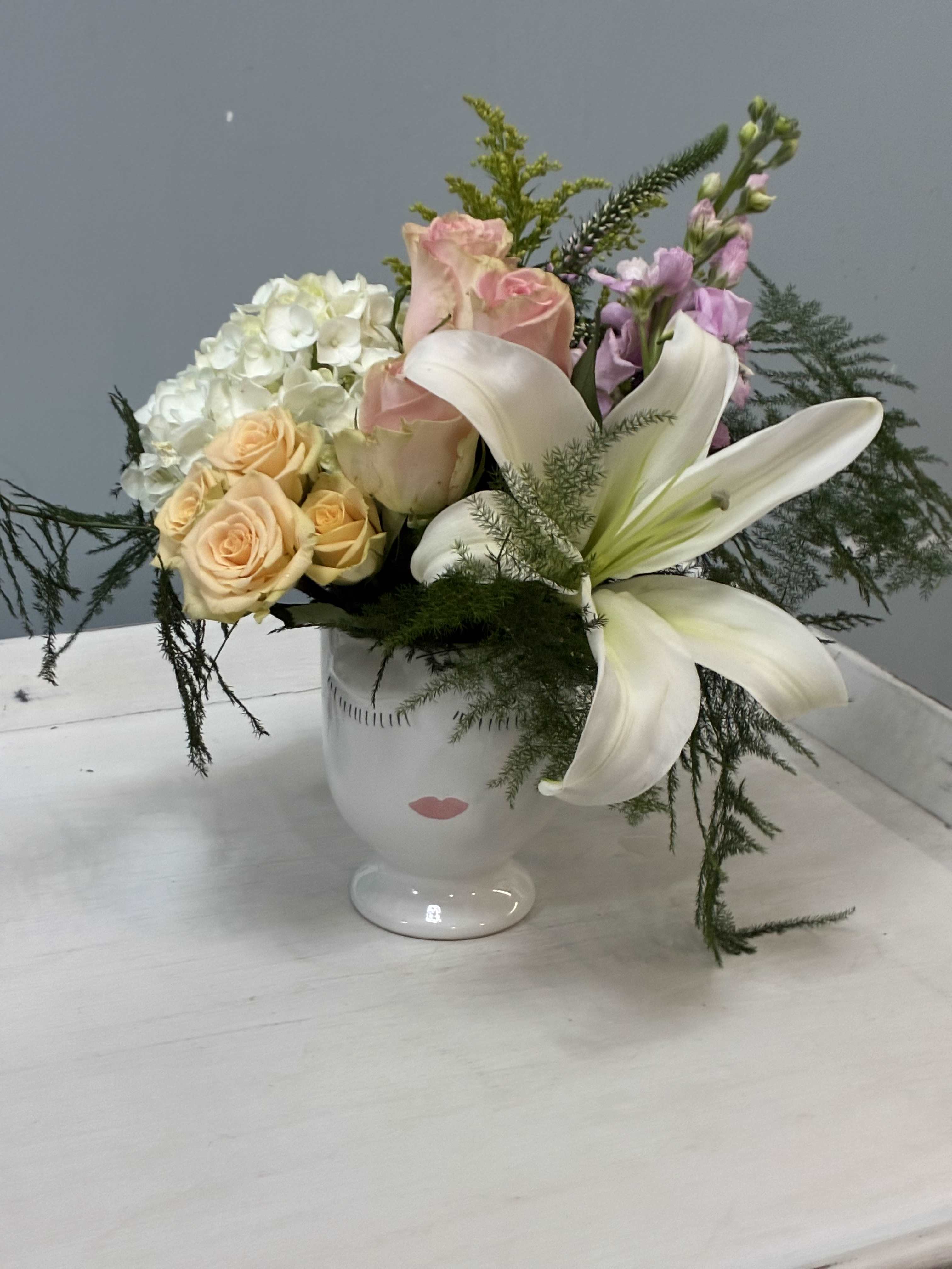 Mixed bouquet with white lilies, roses, and hydrangea in a white vase