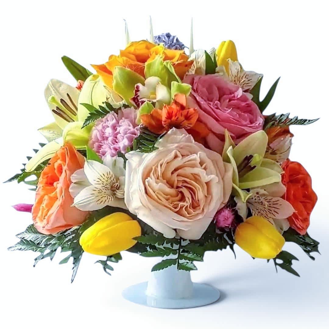 Mixed bouquet of roses, tulips, and lilies in a white pedestal vase
