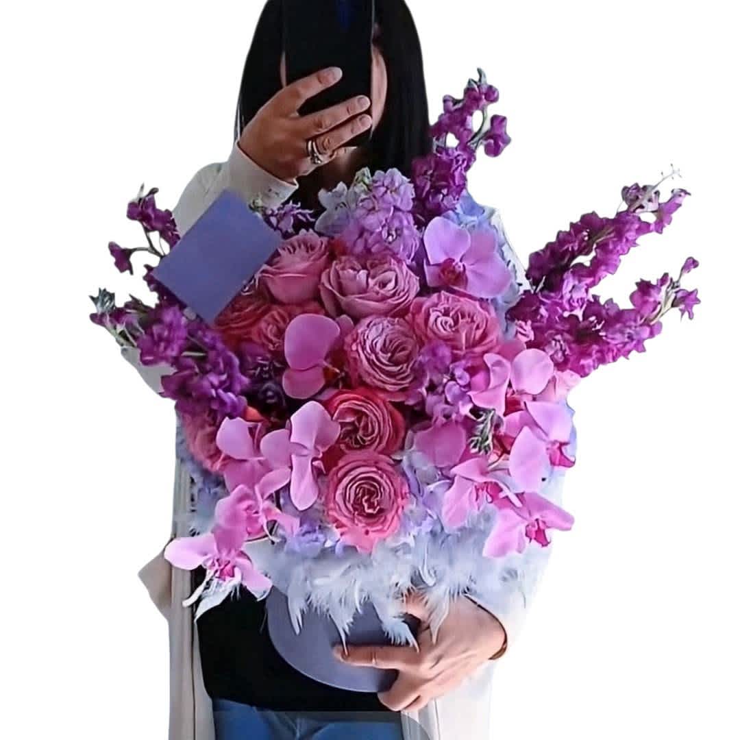 Large bouquet of pink roses and purple orchids in a round box