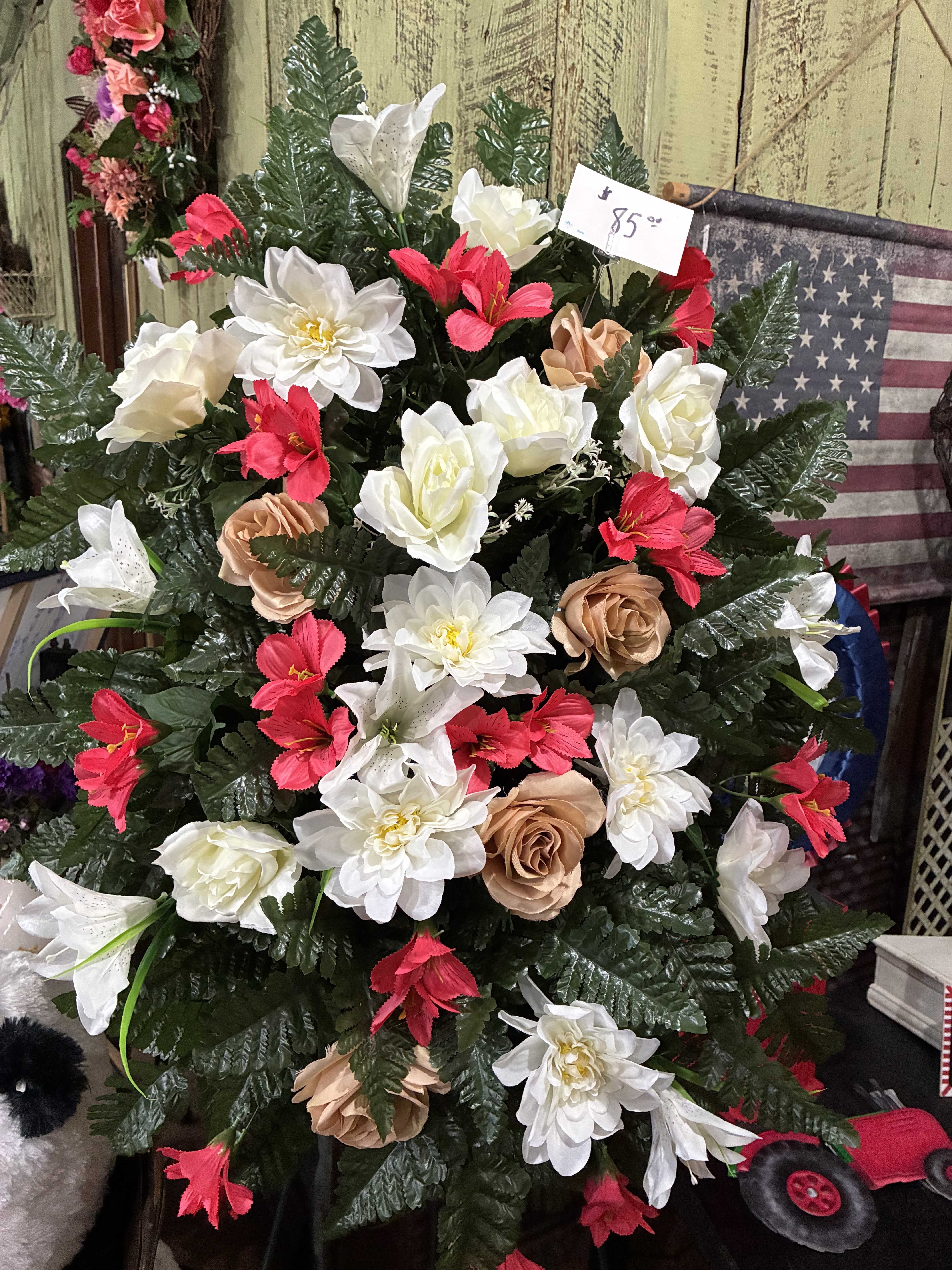 Artificial floral arrangement with white, red, and tan blooms in a dense display