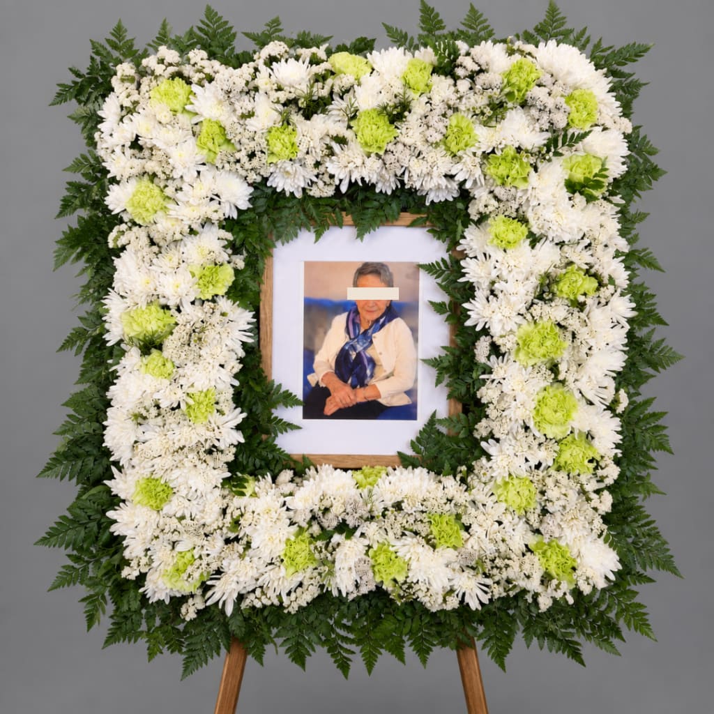 White and lime green funeral wreath around a framed photo on an easel