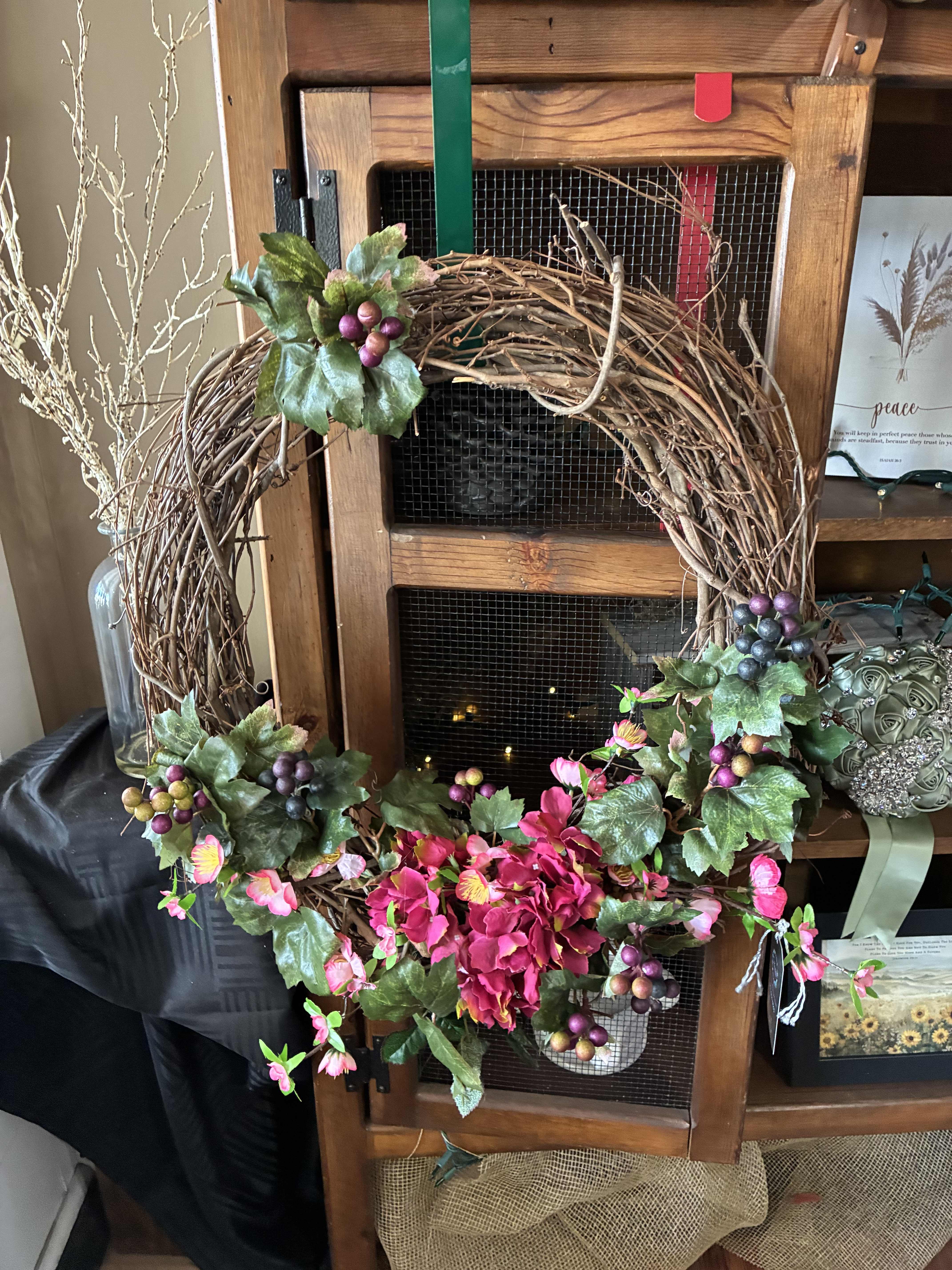 Decorative grapevine wreath with pink flowers and berry clusters