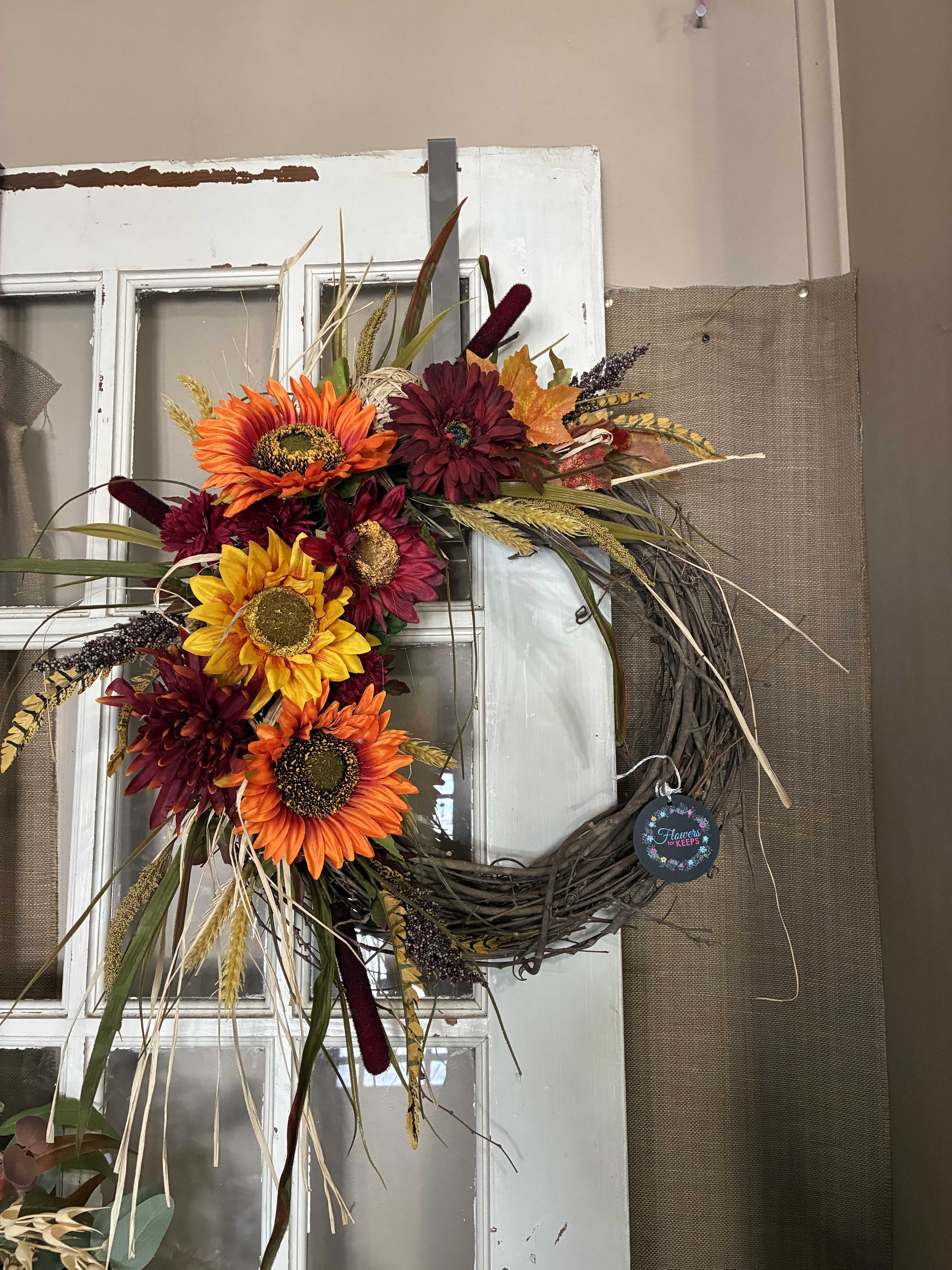 Fall wreath with sunflowers and burgundy flowers on a grapevine ring