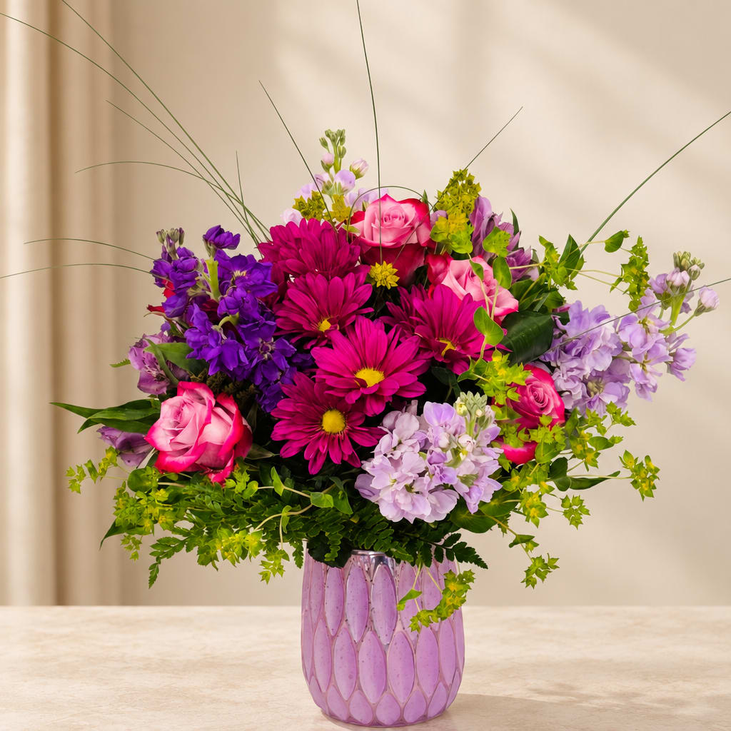 Pink and purple mixed bouquet in a lavender glass vase