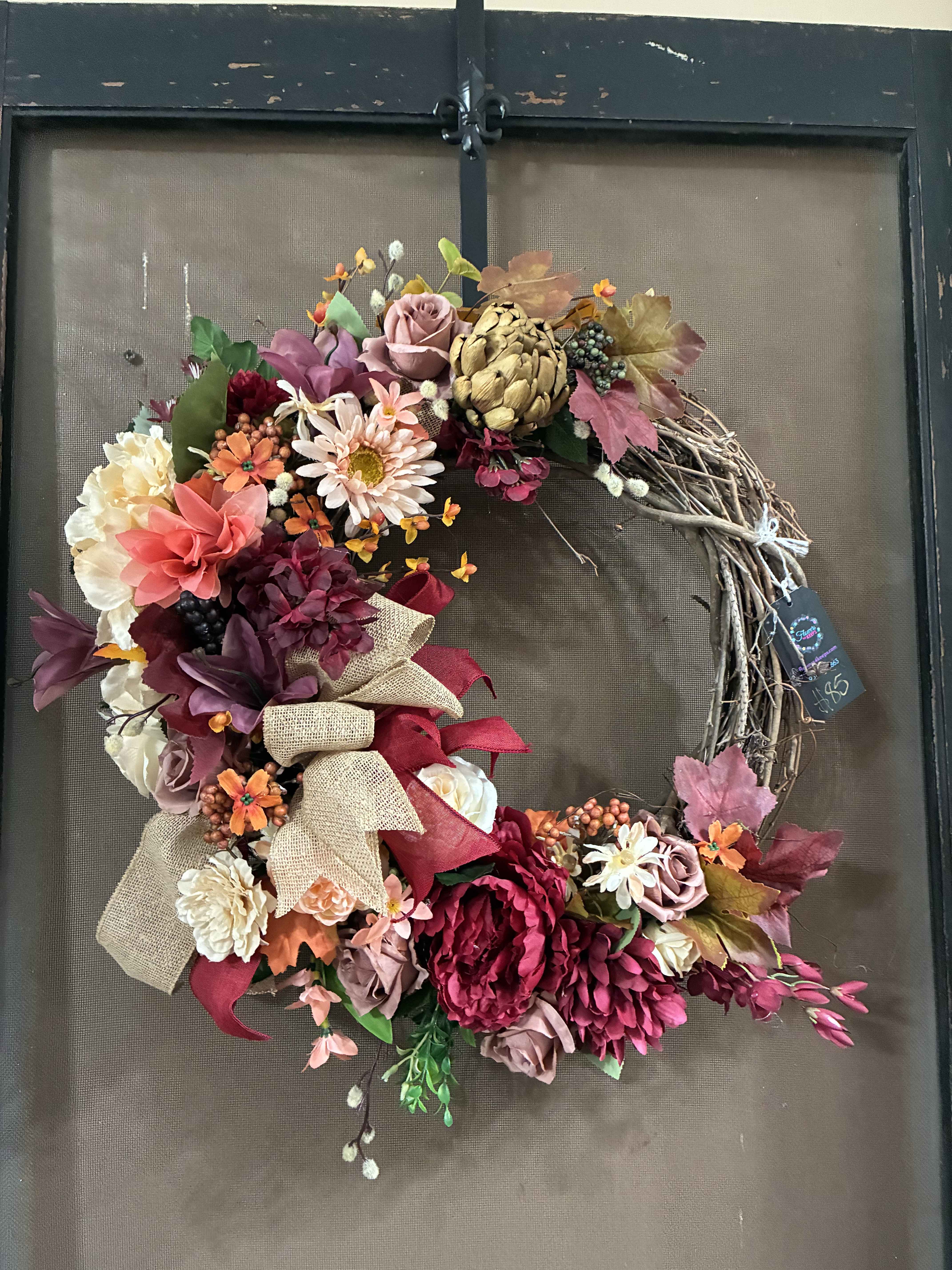 Floral wreath with pink, burgundy, and cream blooms on a twig base